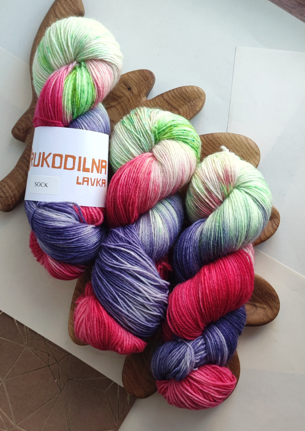 Vibrant neon hand dyed sock yarn in pink green and purple variegated colors on white background