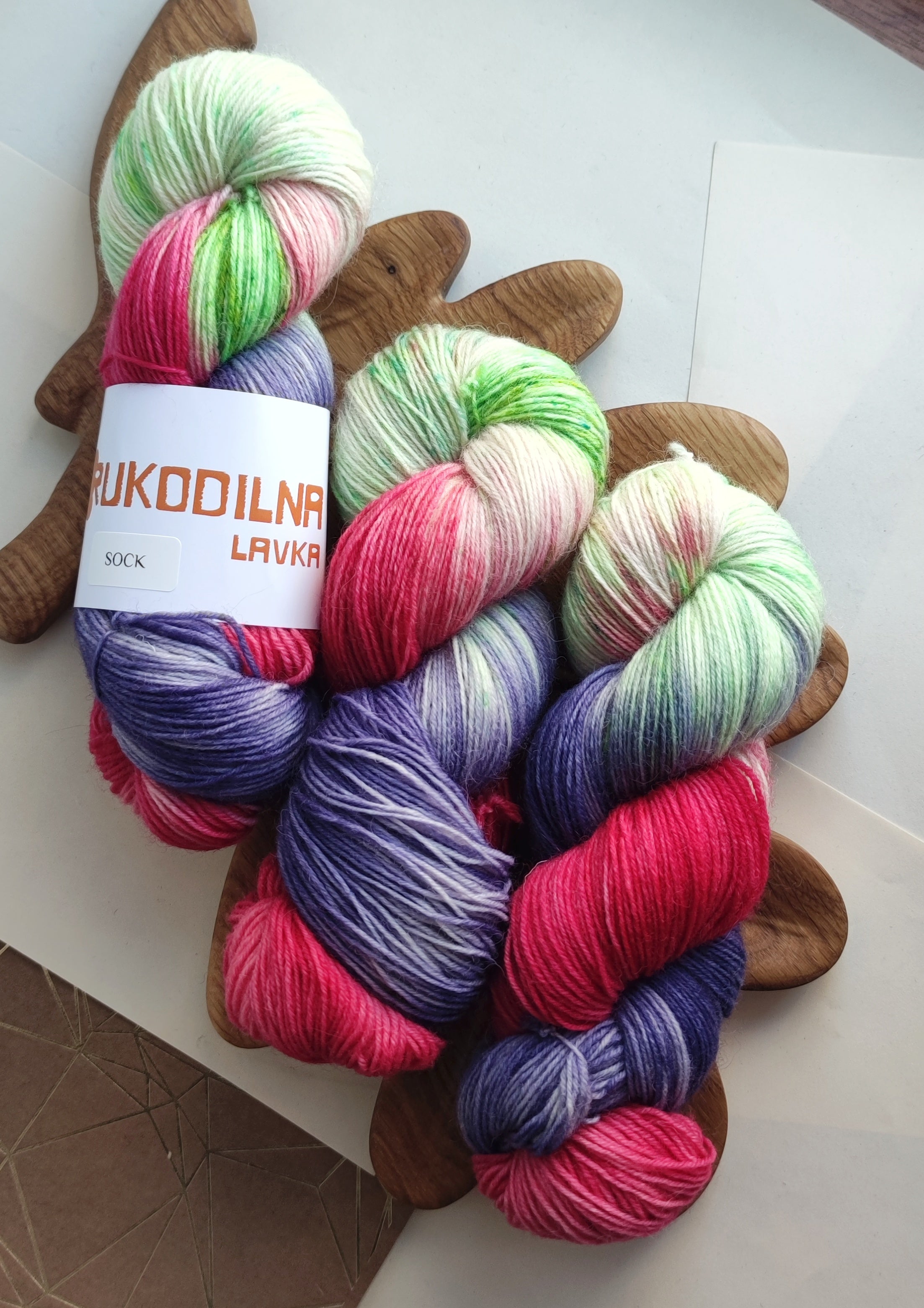 Vibrant neon hand dyed sock yarn in pink green and purple variegated colors on white background