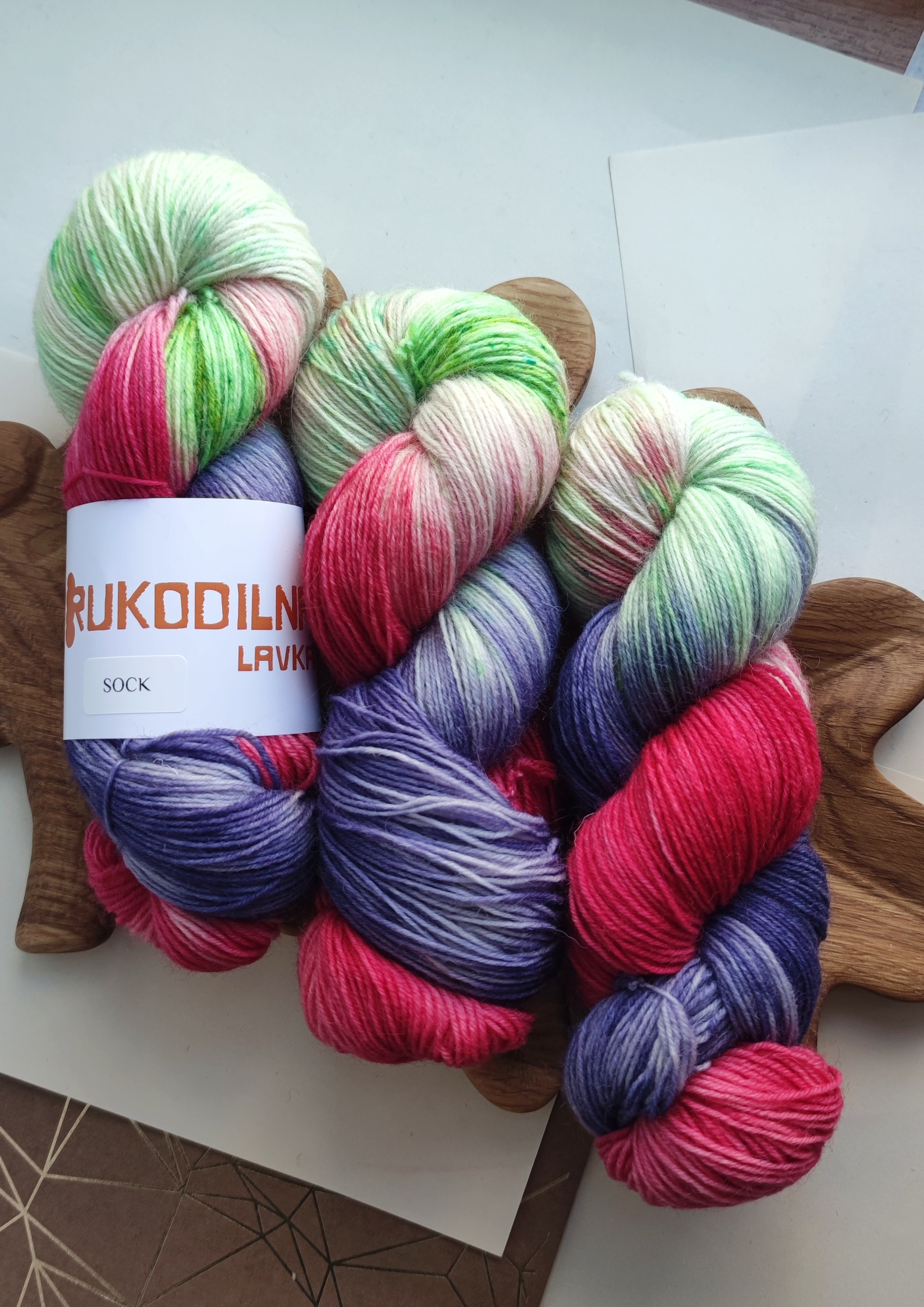 Vibrant neon hand dyed sock yarn in pink green and purple variegated colors on white background