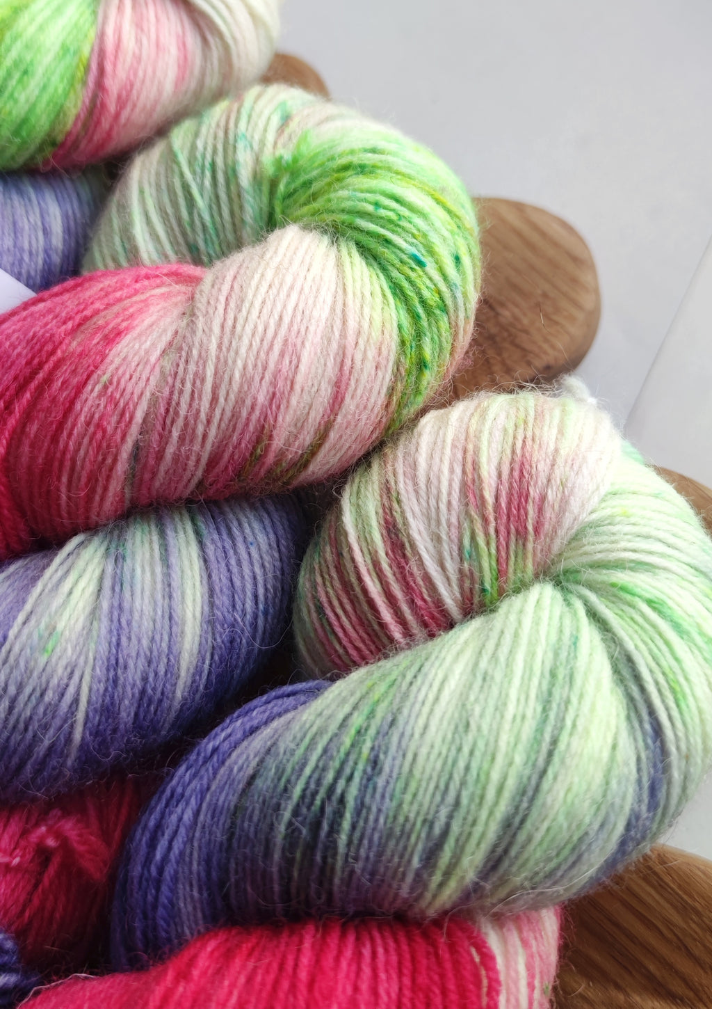 Vibrant neon hand dyed sock yarn in pink green and purple variegated colors on white background