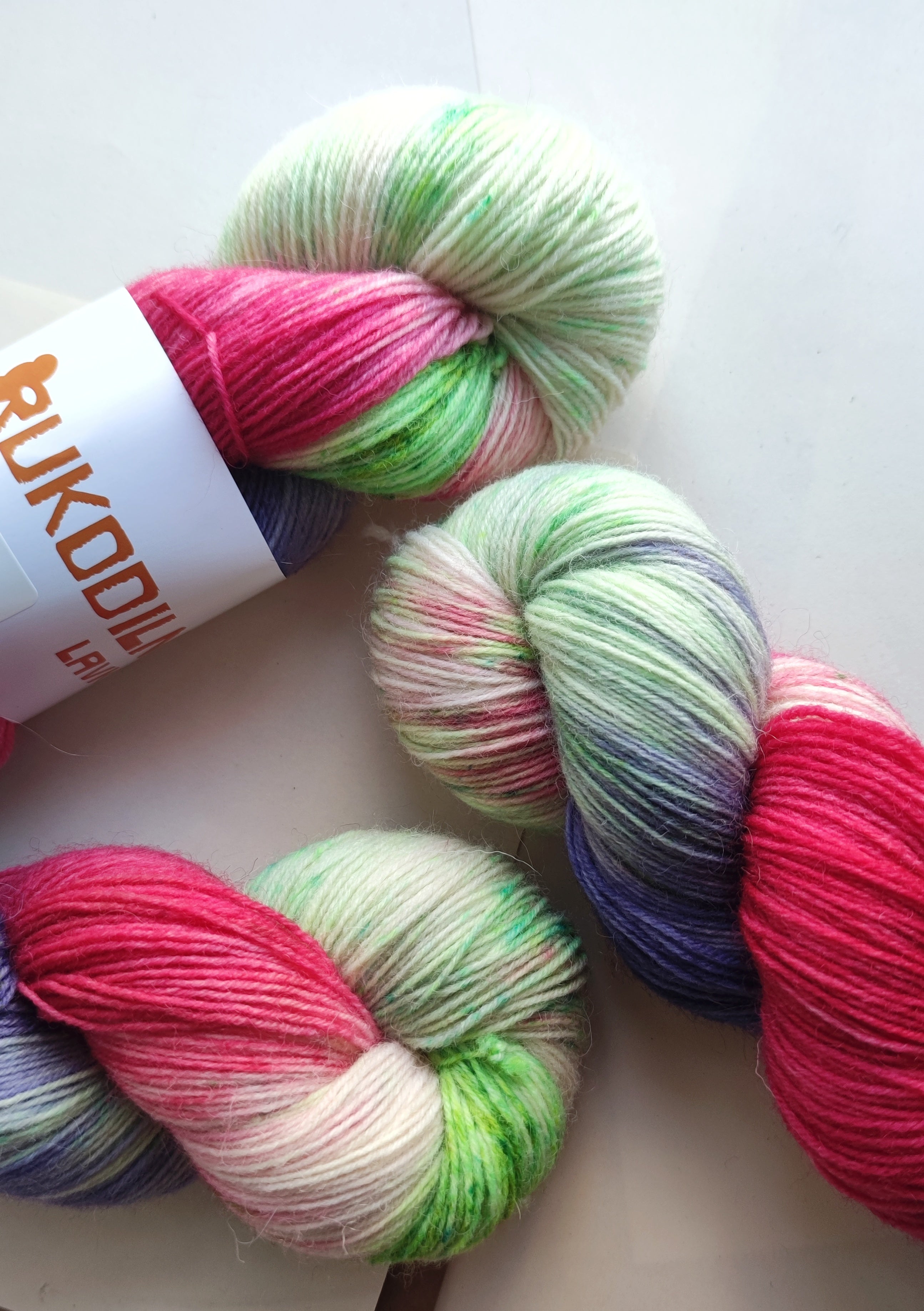 Vibrant neon hand dyed sock yarn in pink green and purple variegated colors on white background
