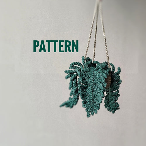 Crochet fern hanging plant pattern with textured green fern leaves and hanging cords on a neutral background.