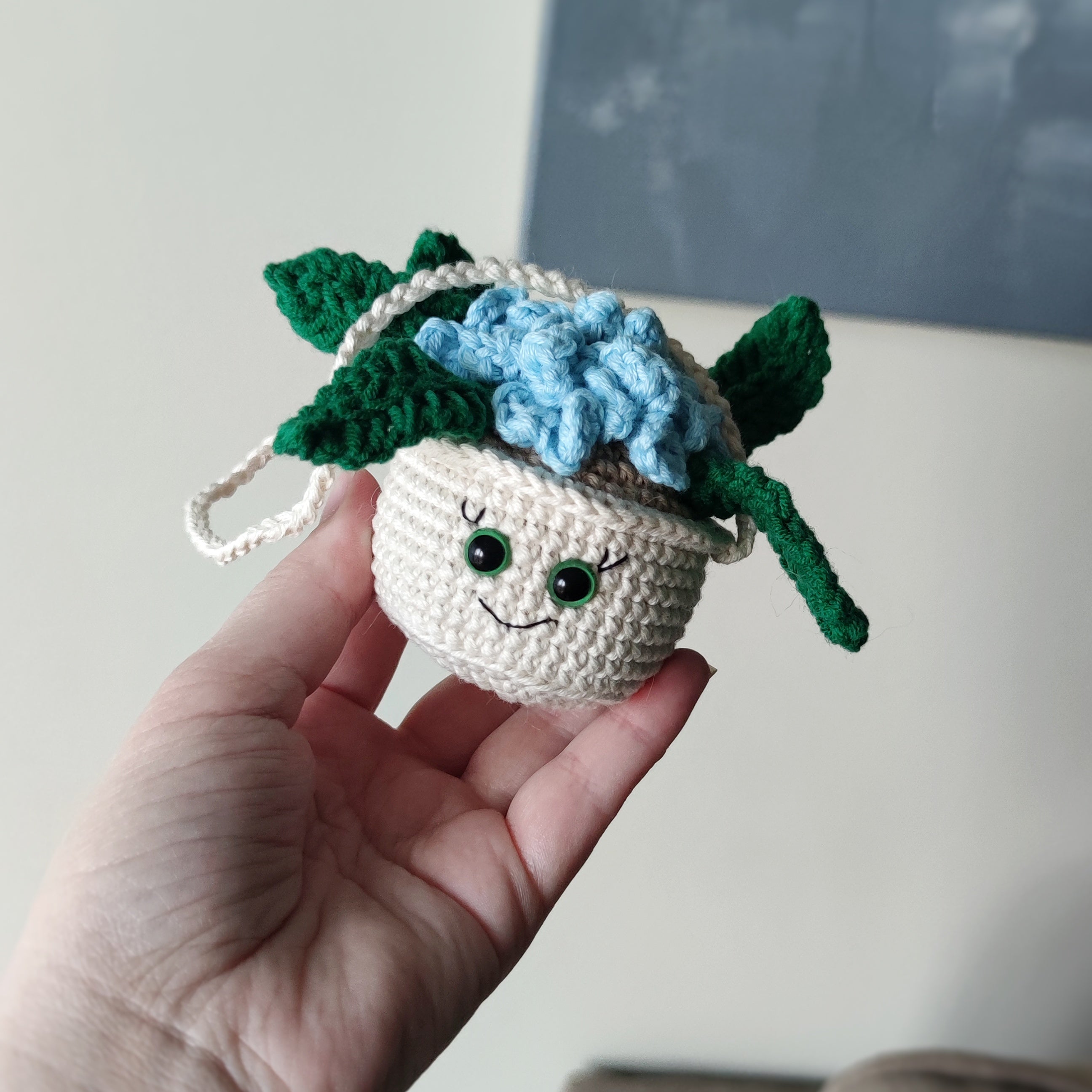 Crochet hanging flower pot with smiling face and blue flowers, handmade amigurumi decor pattern