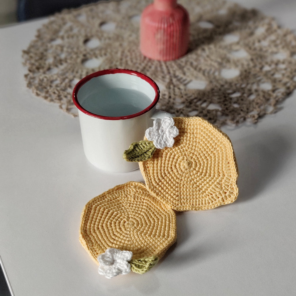 Handmade crochet lemon coasters with white flowers on a table