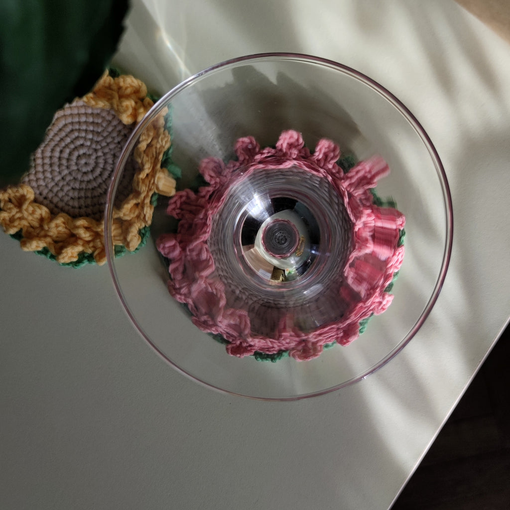 Crochet flower coasters with ruffled edges under cocktail glasses