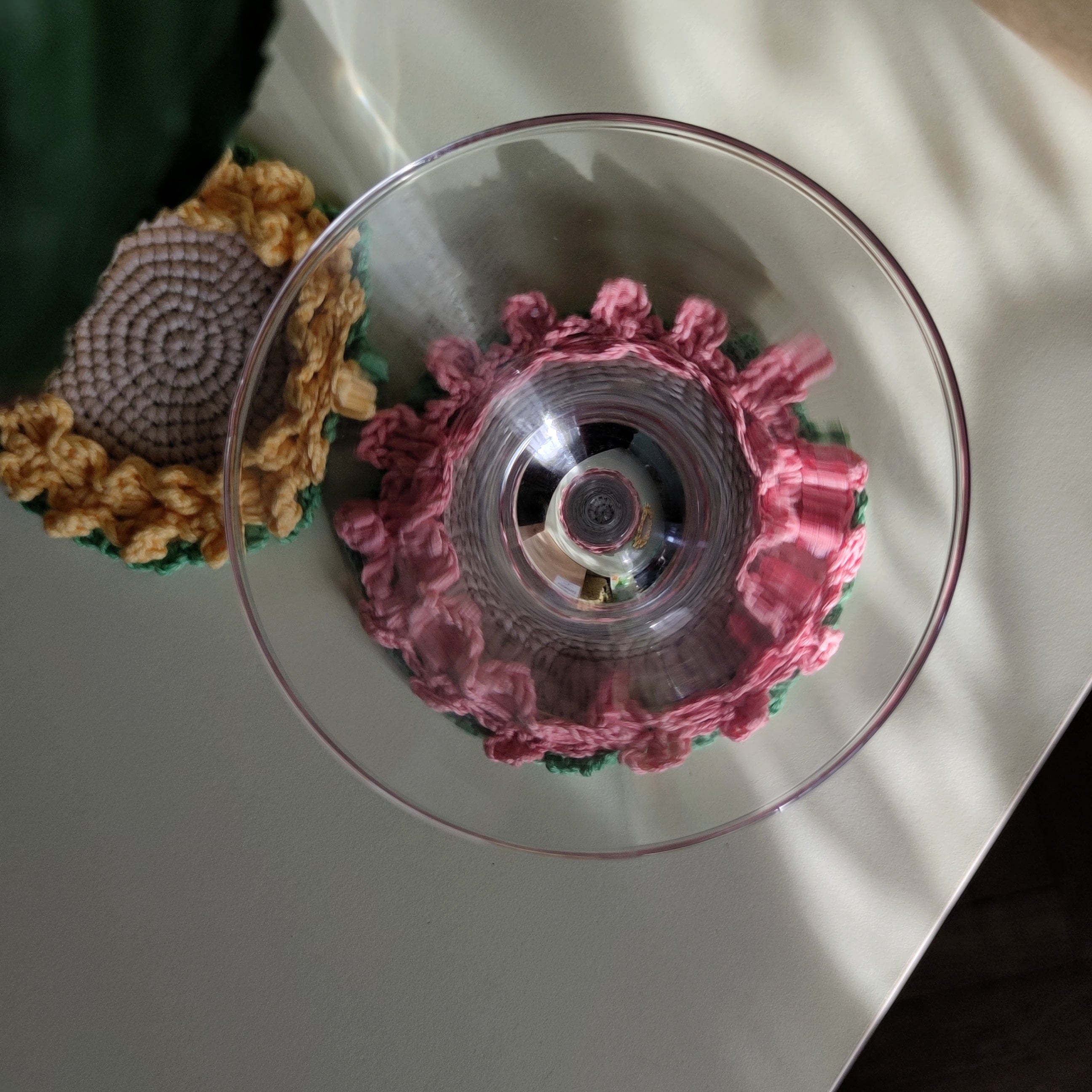 Crochet flower coasters with ruffled edges under cocktail glasses