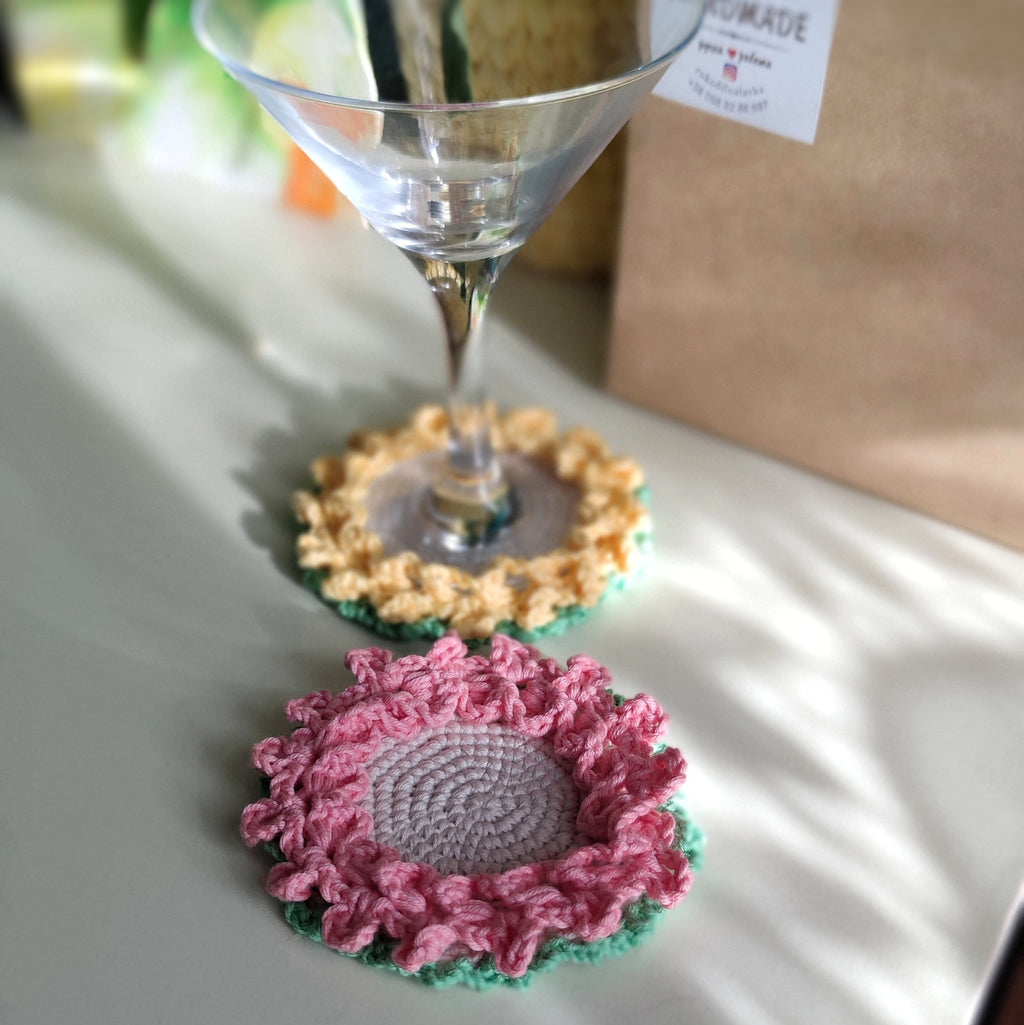 Crochet flower coasters with ruffled edges under cocktail glasses