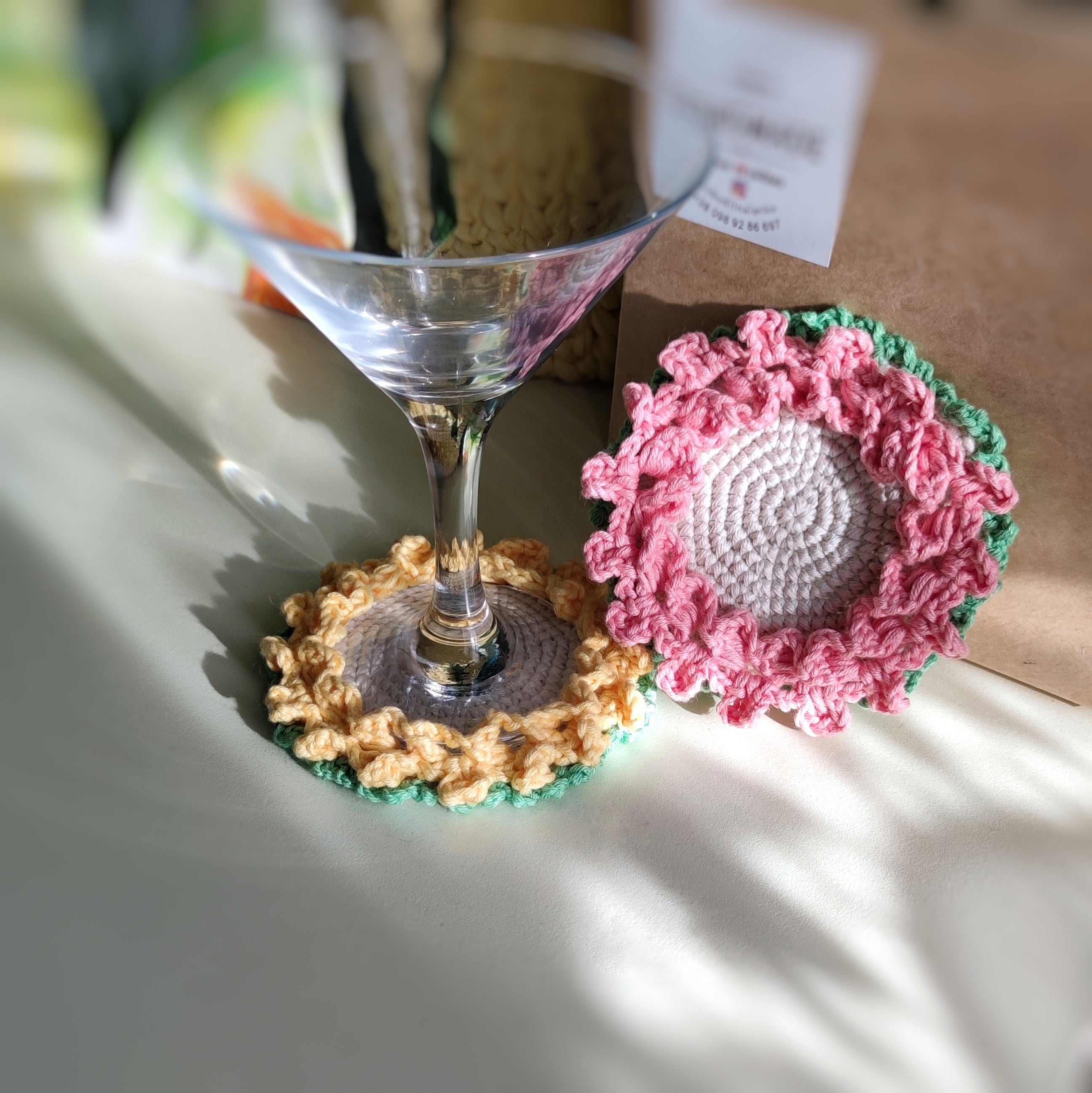 Crochet flower coasters with ruffled edges under cocktail glasses