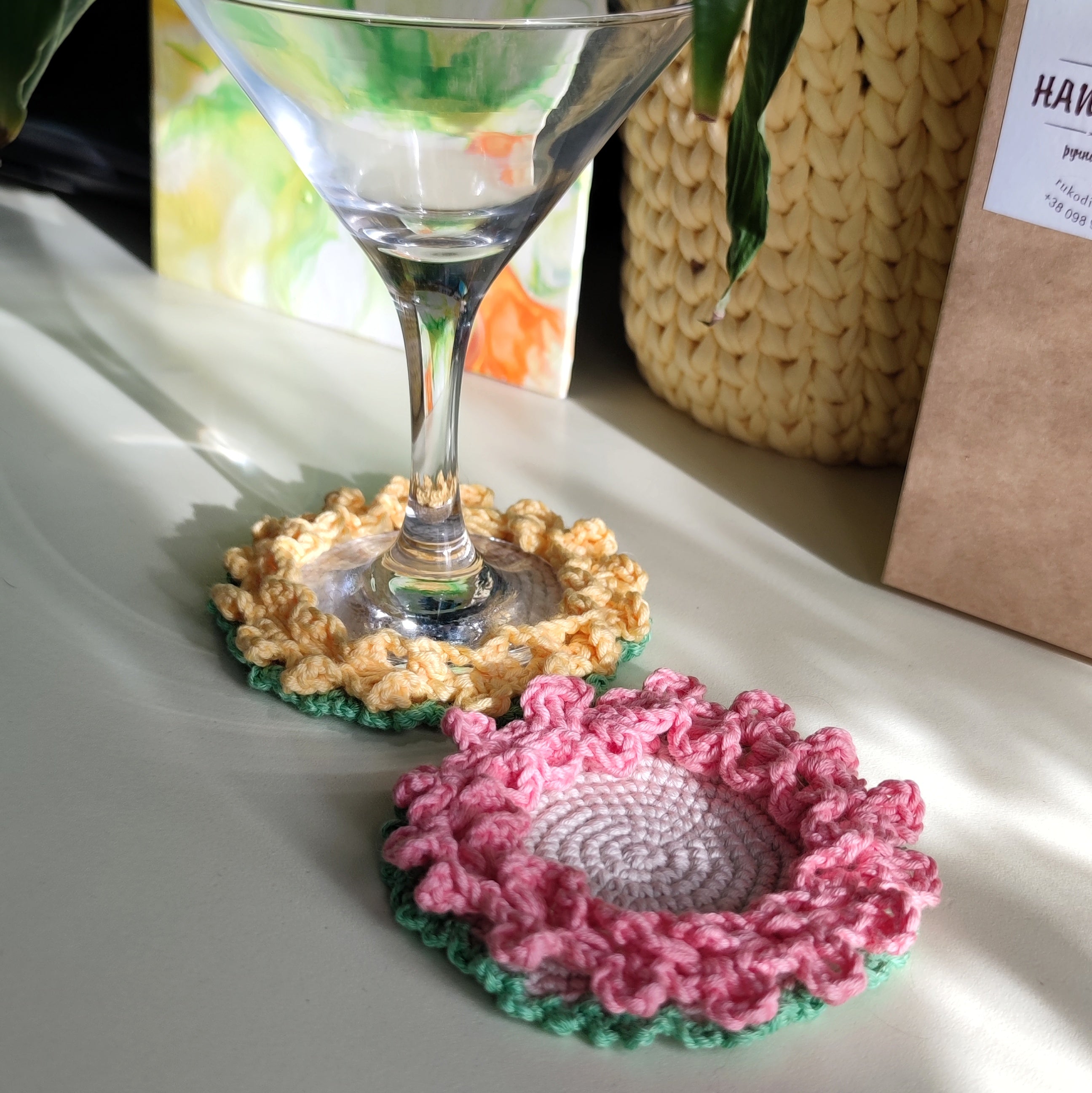 Crochet flower coasters with ruffled edges under cocktail glasses