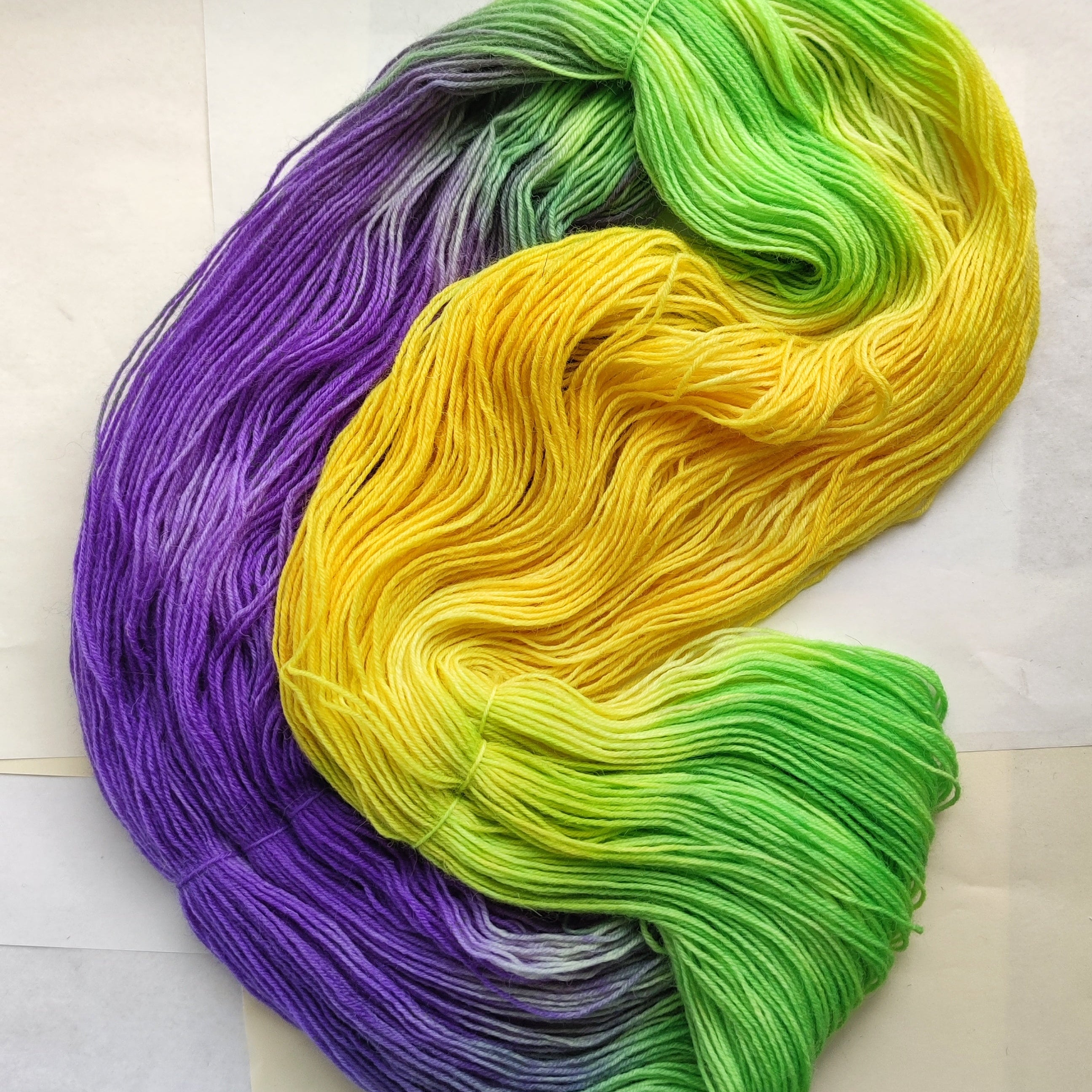 Hand dyed sock yarn skeins in purple, yellow and green variegated colors inspired by spring flowers