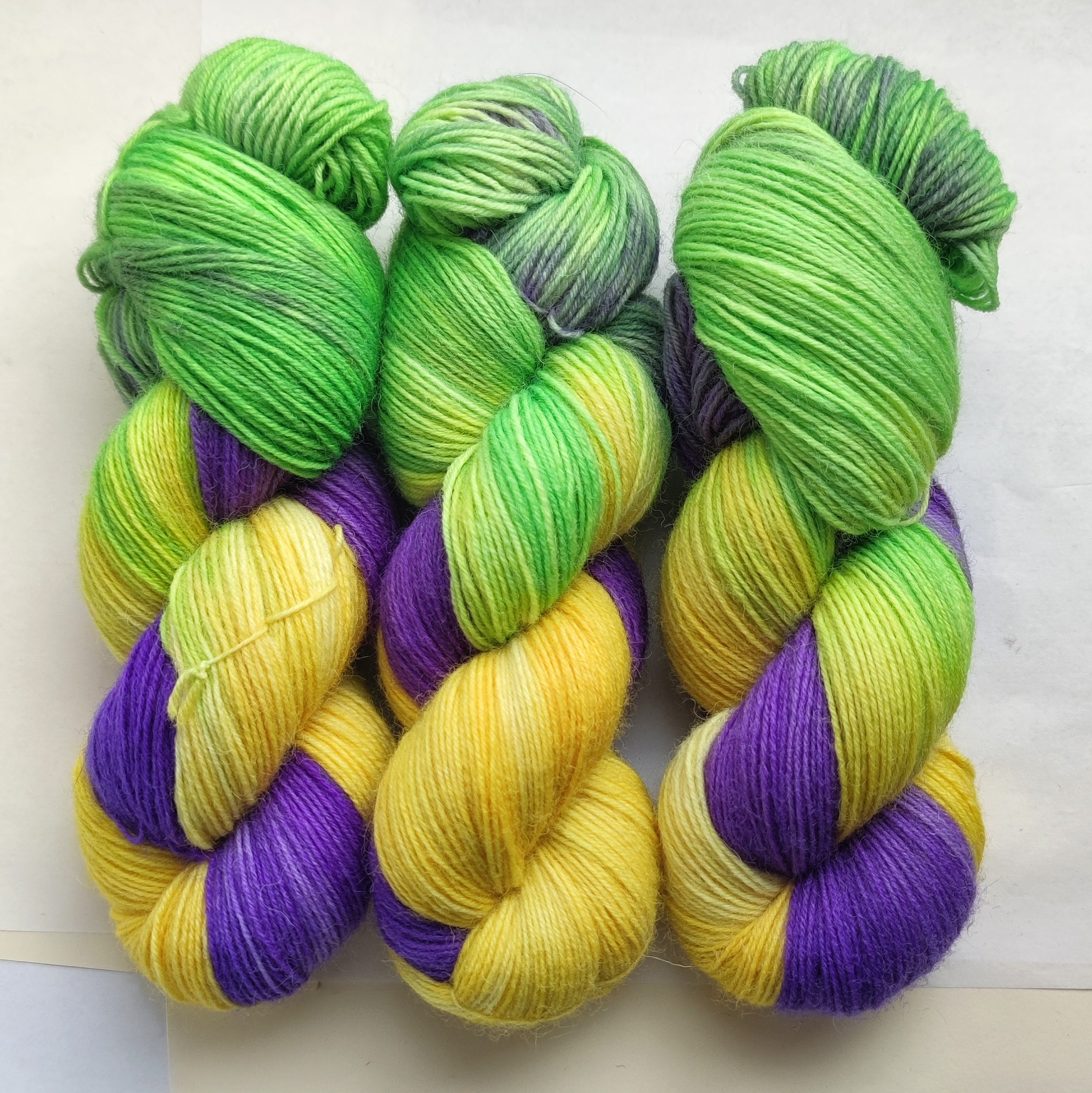 Hand dyed sock yarn skeins in purple, yellow and green variegated colors inspired by spring flowers