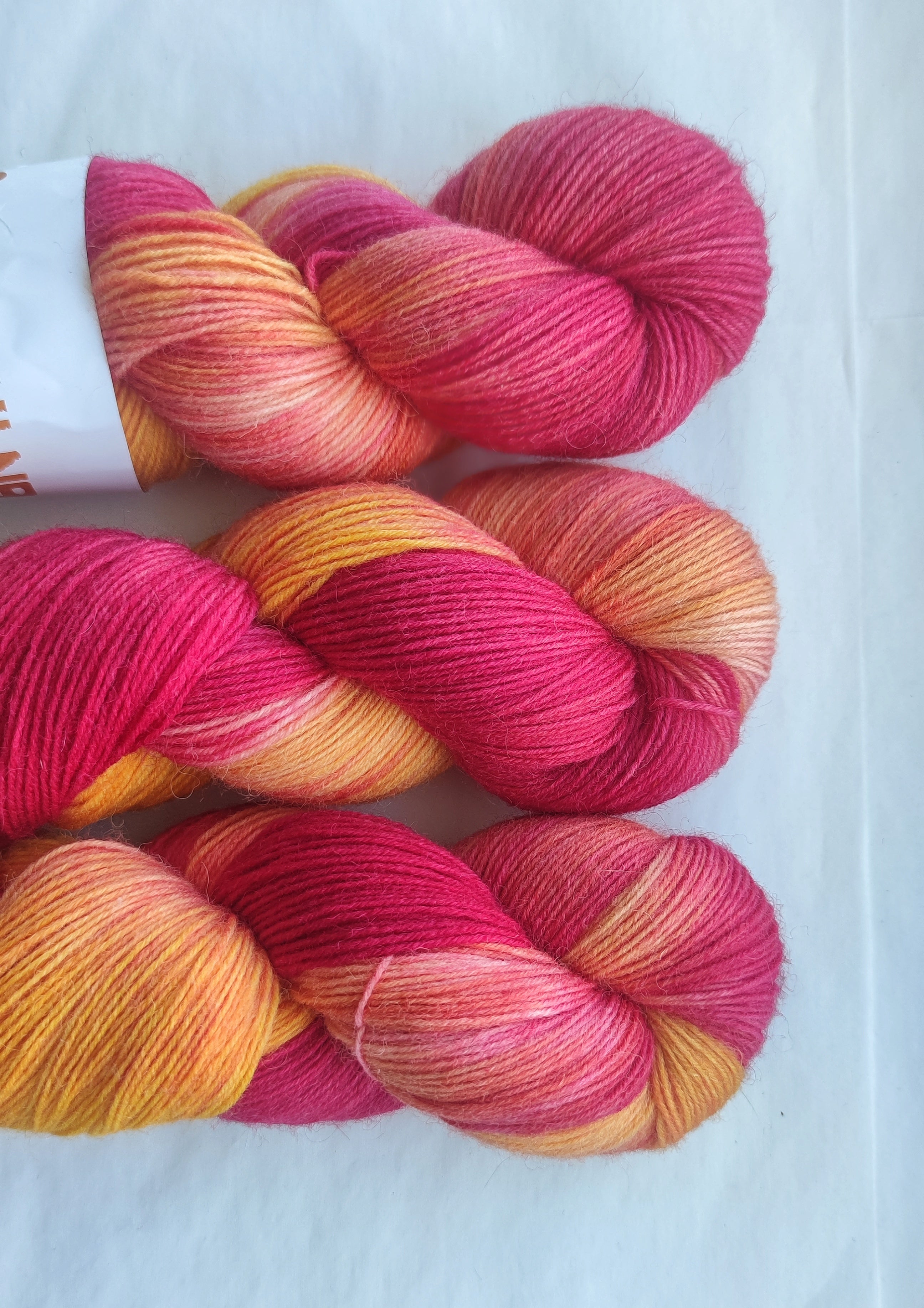 Hand dyed pink orange variegated sock yarn skeins with bright floral inspired color palette