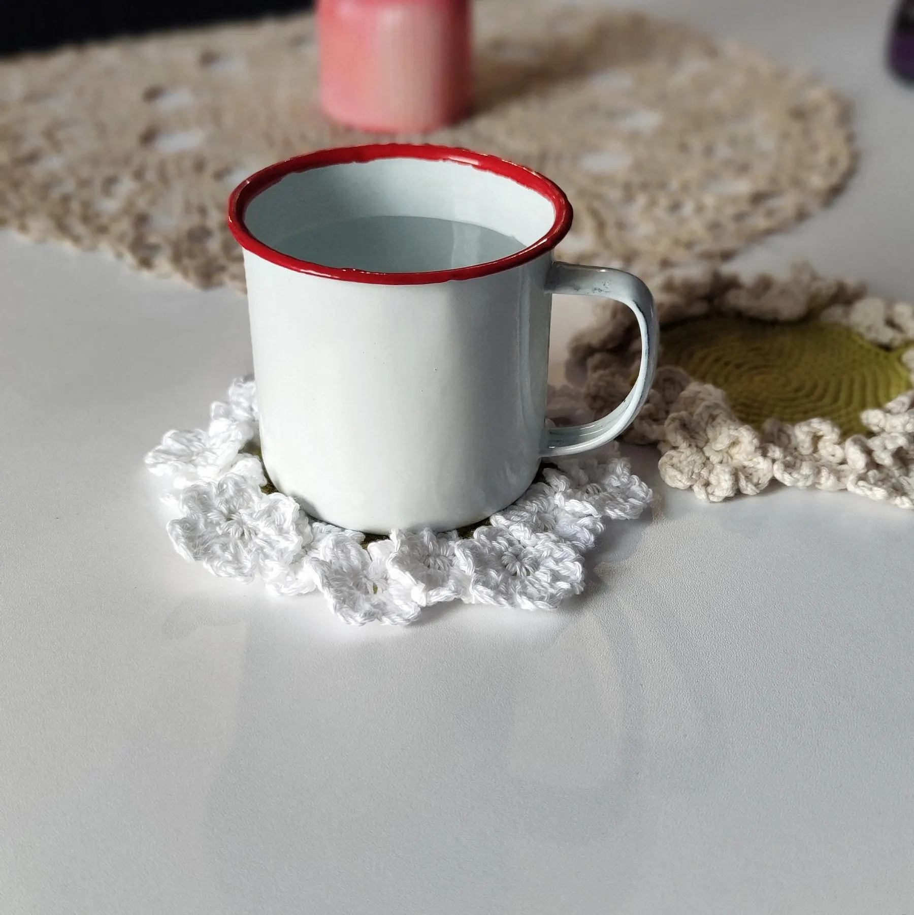 Flower crochet coaster with ruffled edge under coffee mug