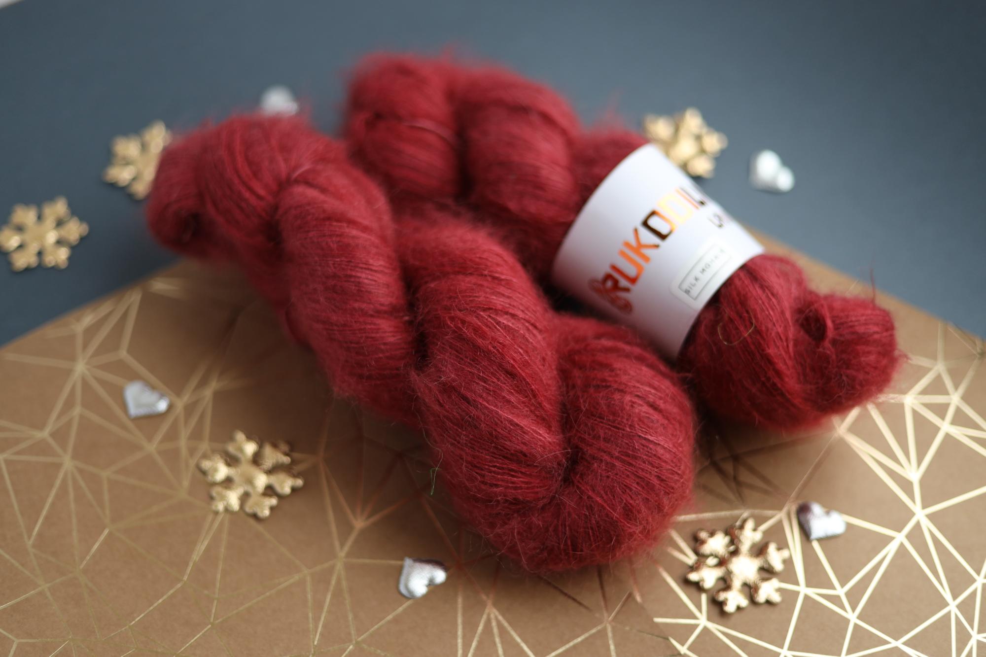 Hand-dyed ruby red silk mohair yarn skein close-up showing airy lace weight texture