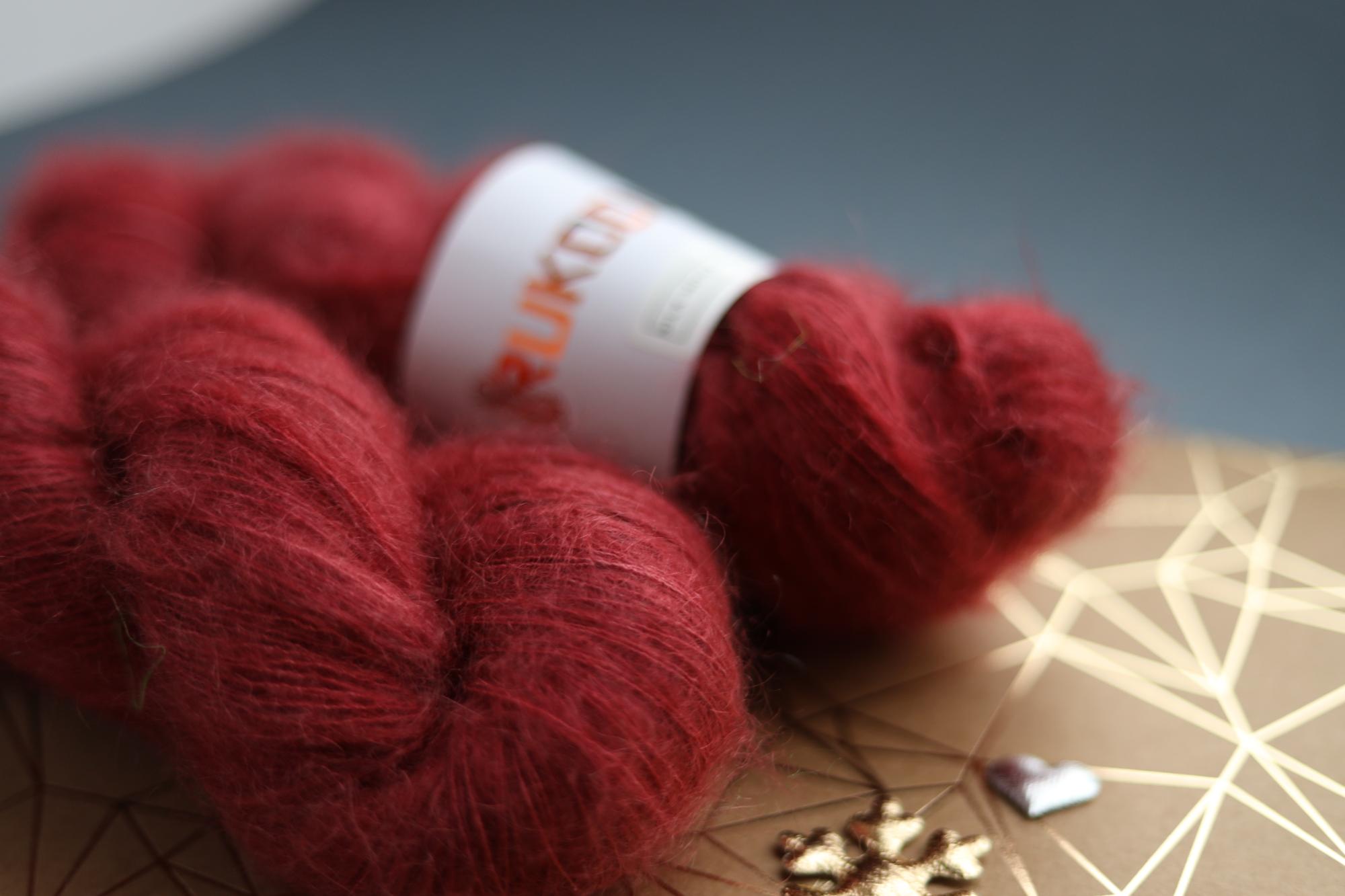 Hand-dyed ruby red silk mohair yarn skein close-up showing airy lace weight texture