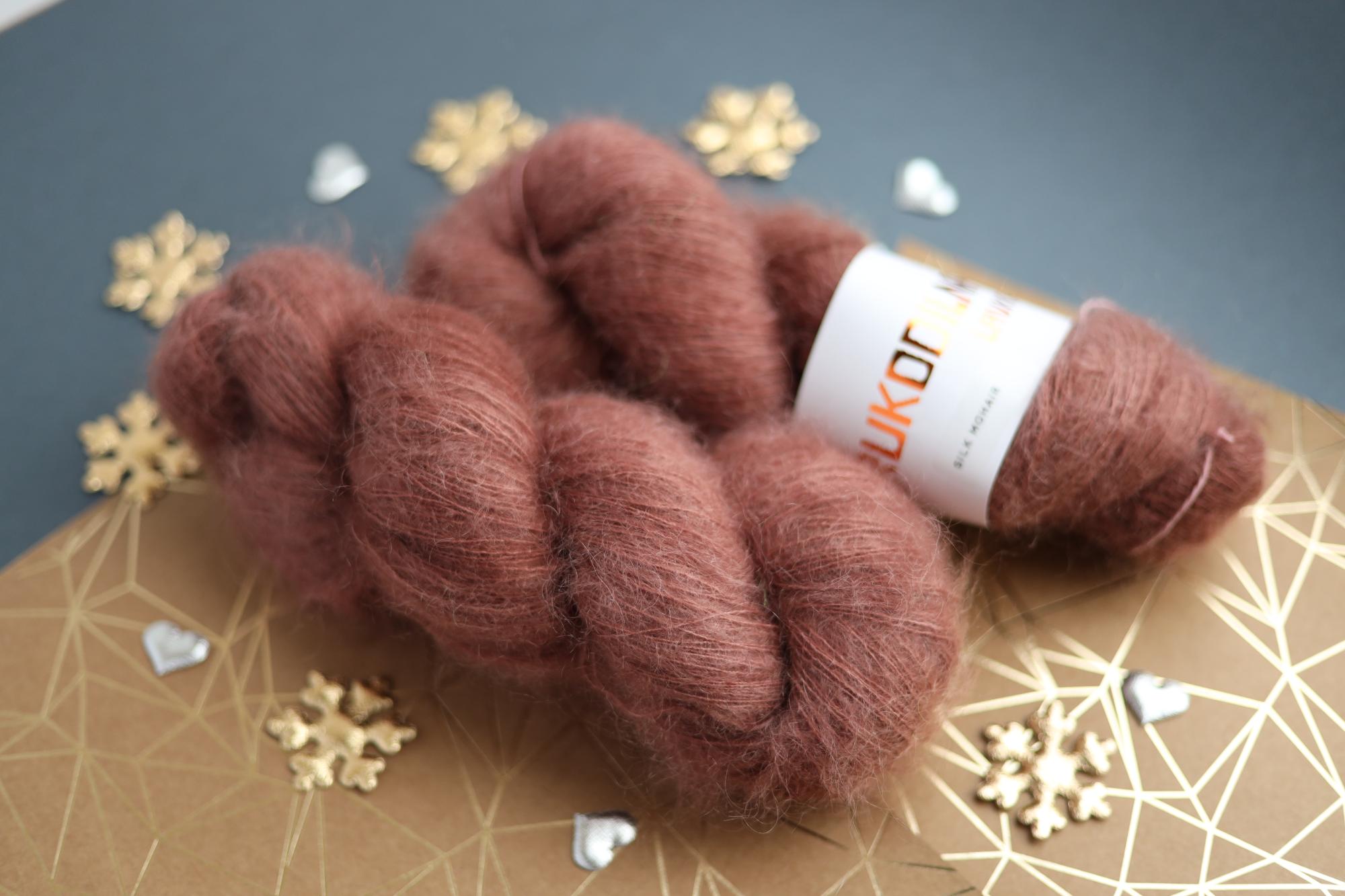 Close-up of hand-dyed brown silk mohair yarn showing airy lace weight texture