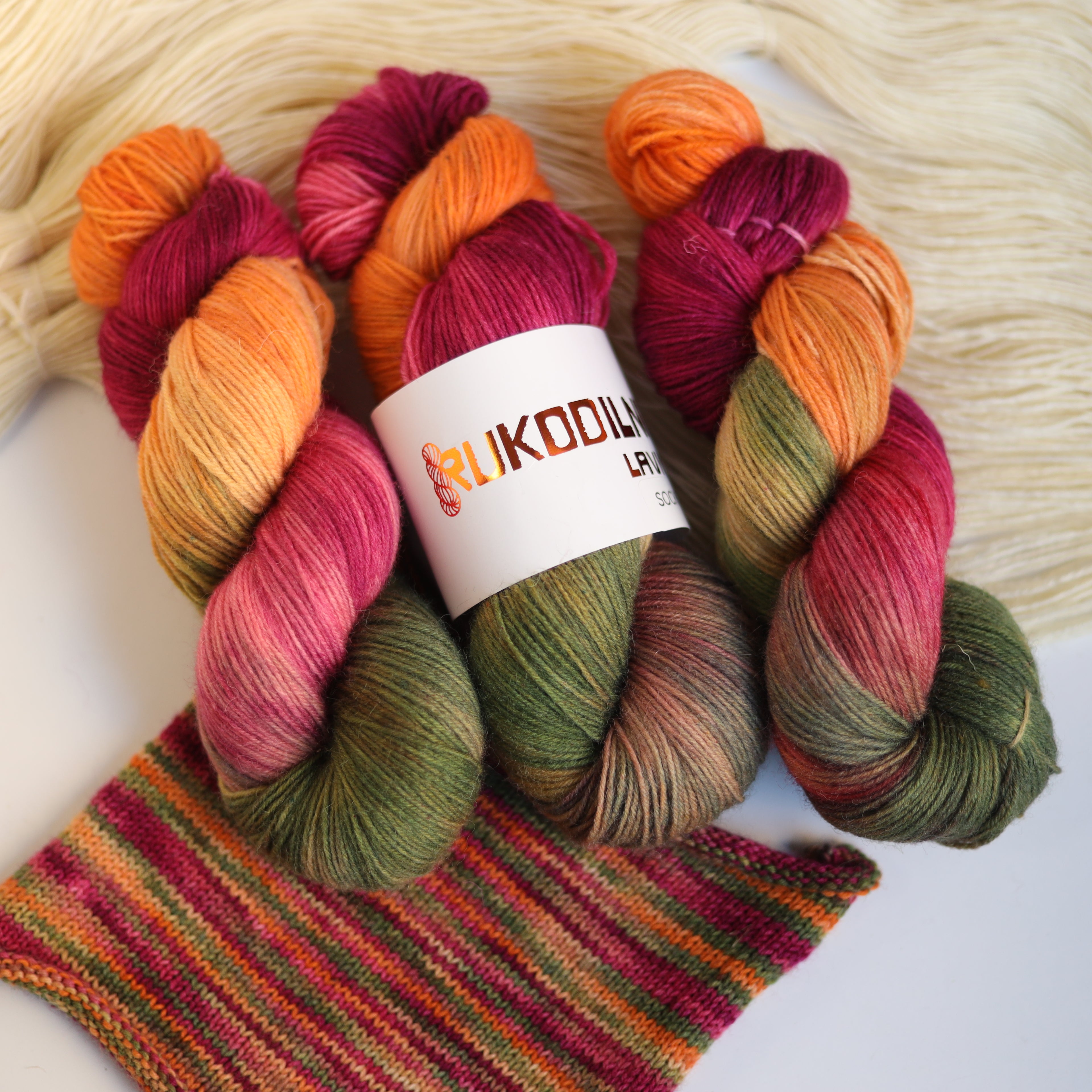 Hand dyed fingering sock yarn skeins in variegated autumn colors with knitted sock swatch
