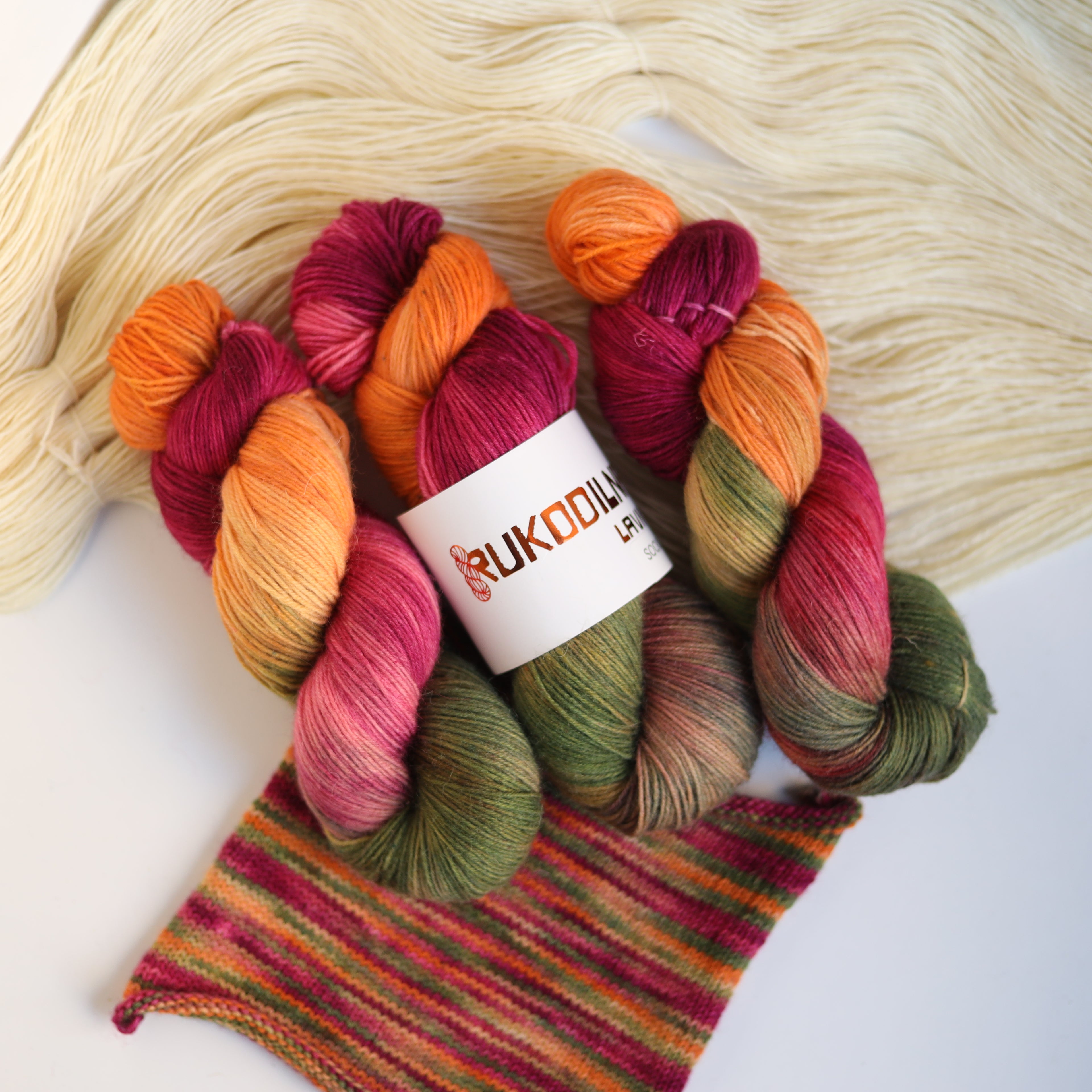 Hand dyed fingering sock yarn skeins in variegated autumn colors with knitted sock swatch