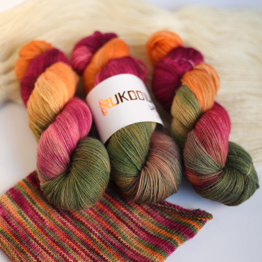 Hand dyed fingering sock yarn skeins in variegated autumn colors with knitted sock swatch