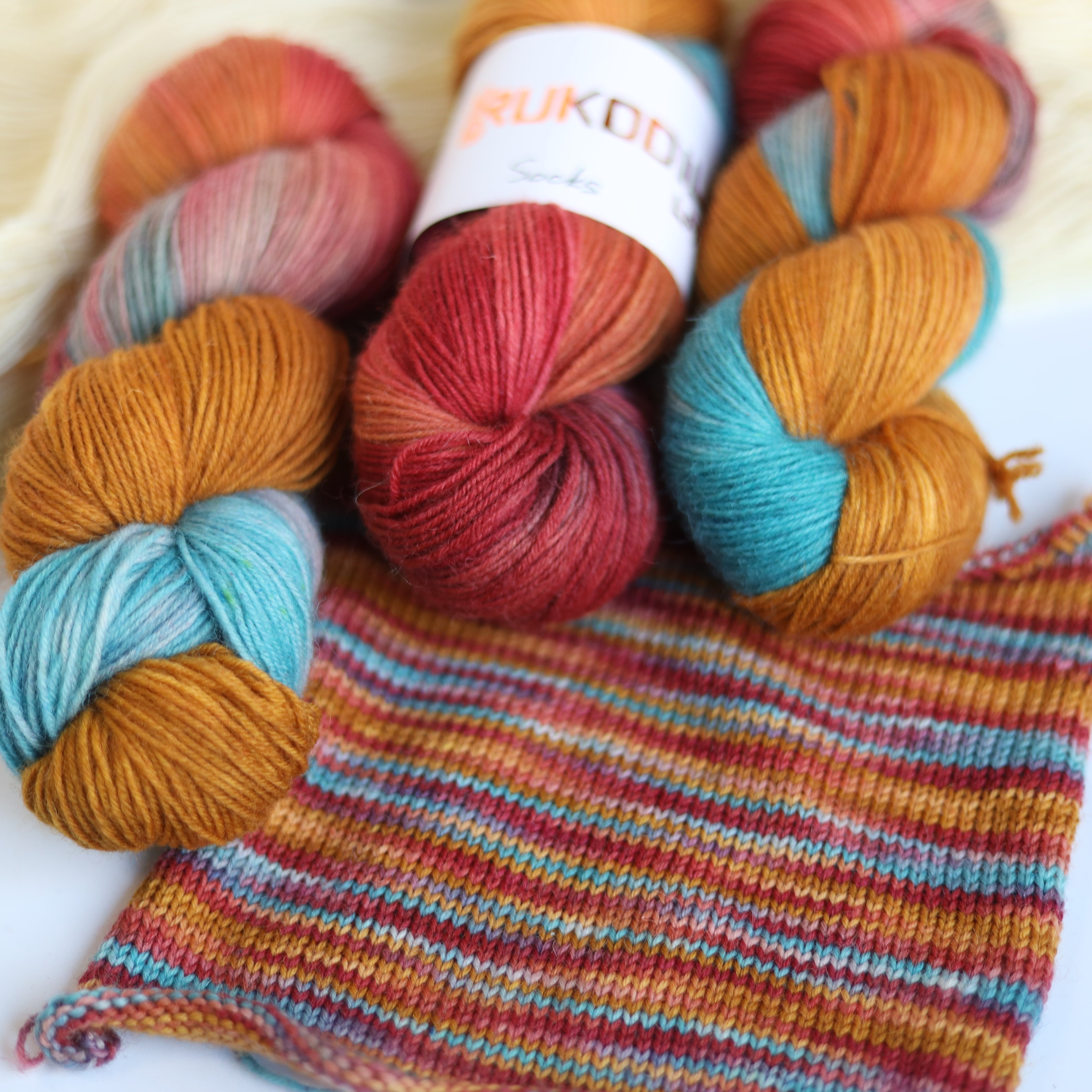 Hand dyed rust and teal sock yarn made from Italian superwash wool with knitted sock swatch, fingering weight 4-ply yarn dyed in Ukraine