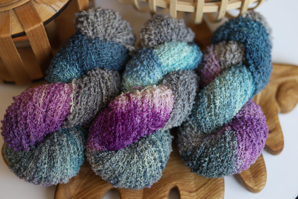 Hand dyed purple blue boucle yarn made from merino wool blend with textured fluffy loop structure