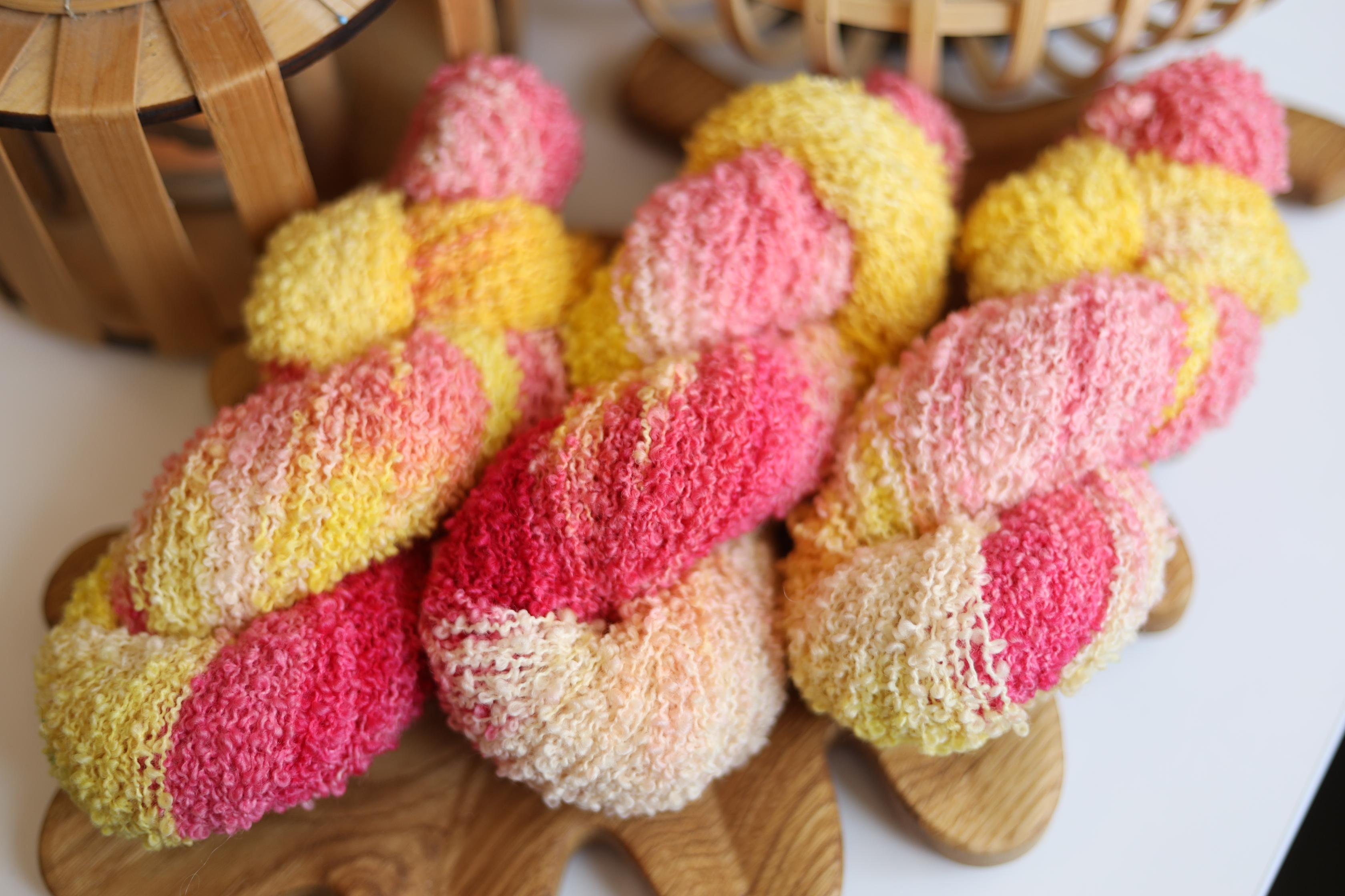 Hand dyed pink yellow boucle yarn made from merino wool blend with soft textured boucle structure