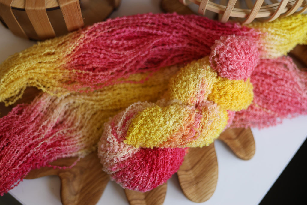 Hand dyed pink yellow boucle yarn made from merino wool blend with soft textured boucle structure