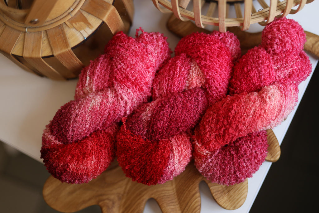 Hand dyed raspberry pink boucle yarn made from merino wool blend with soft textured boucle structure