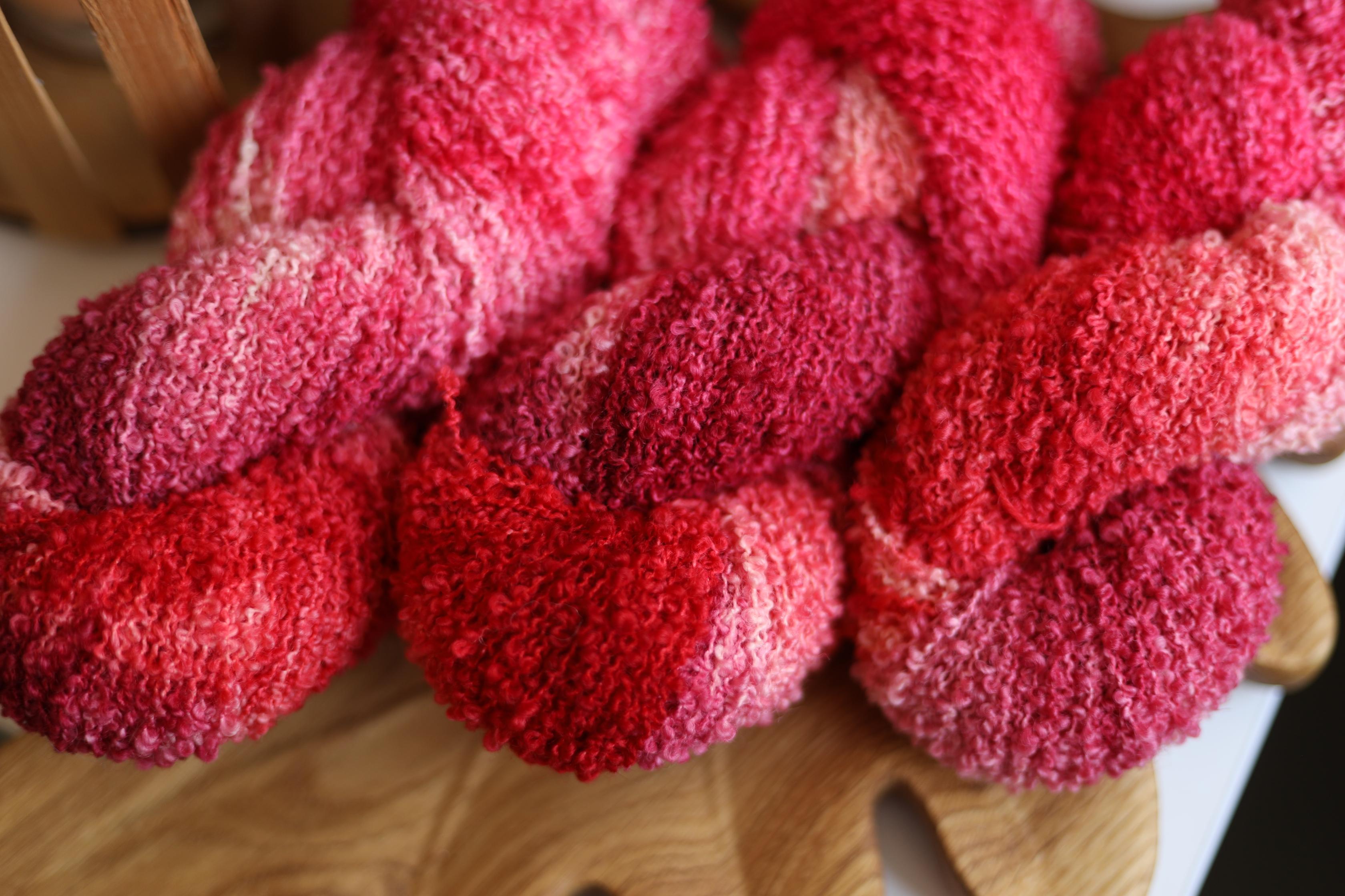Hand dyed raspberry pink boucle yarn made from merino wool blend with soft textured boucle structure