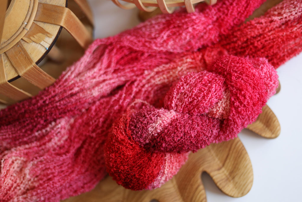 Hand dyed raspberry pink boucle yarn made from merino wool blend with soft textured boucle structure
