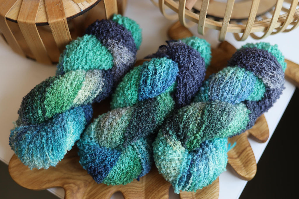 Blue green textured boucle yarn made from merino wool blend with fluffy loop texture for knitting and crochet