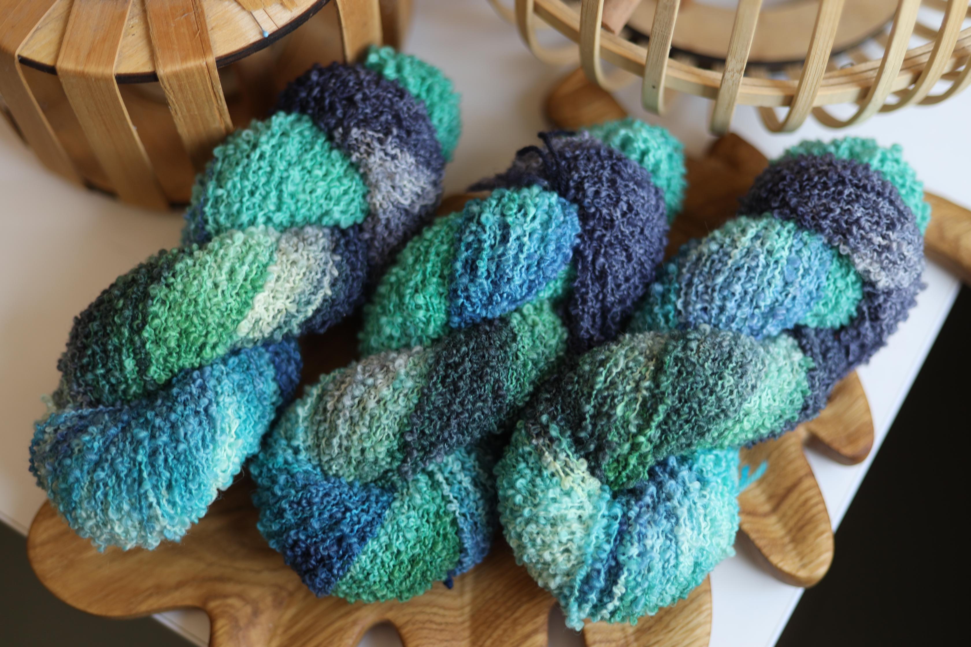 Blue green textured boucle yarn made from merino wool blend with fluffy loop texture for knitting and crochet