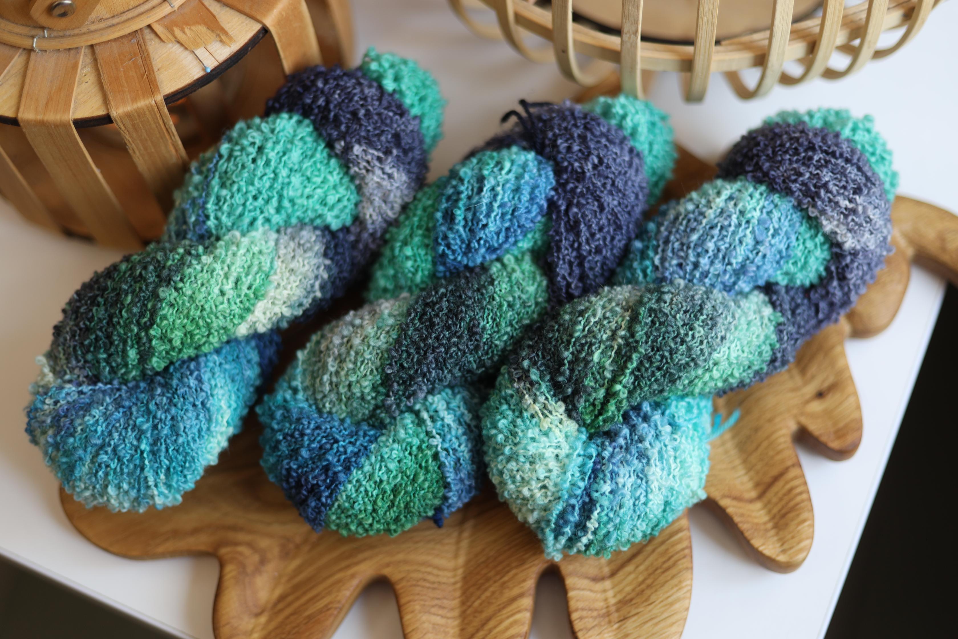 Blue green textured boucle yarn made from merino wool blend with fluffy loop texture for knitting and crochet