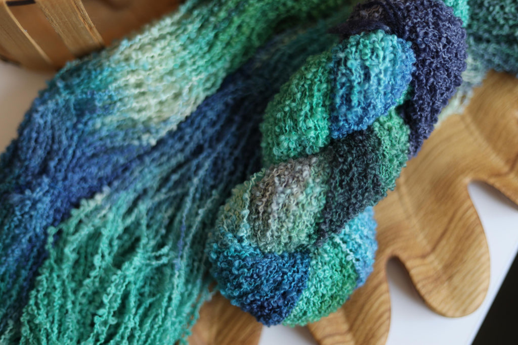 Blue green textured boucle yarn made from merino wool blend with fluffy loop texture for knitting and crochet