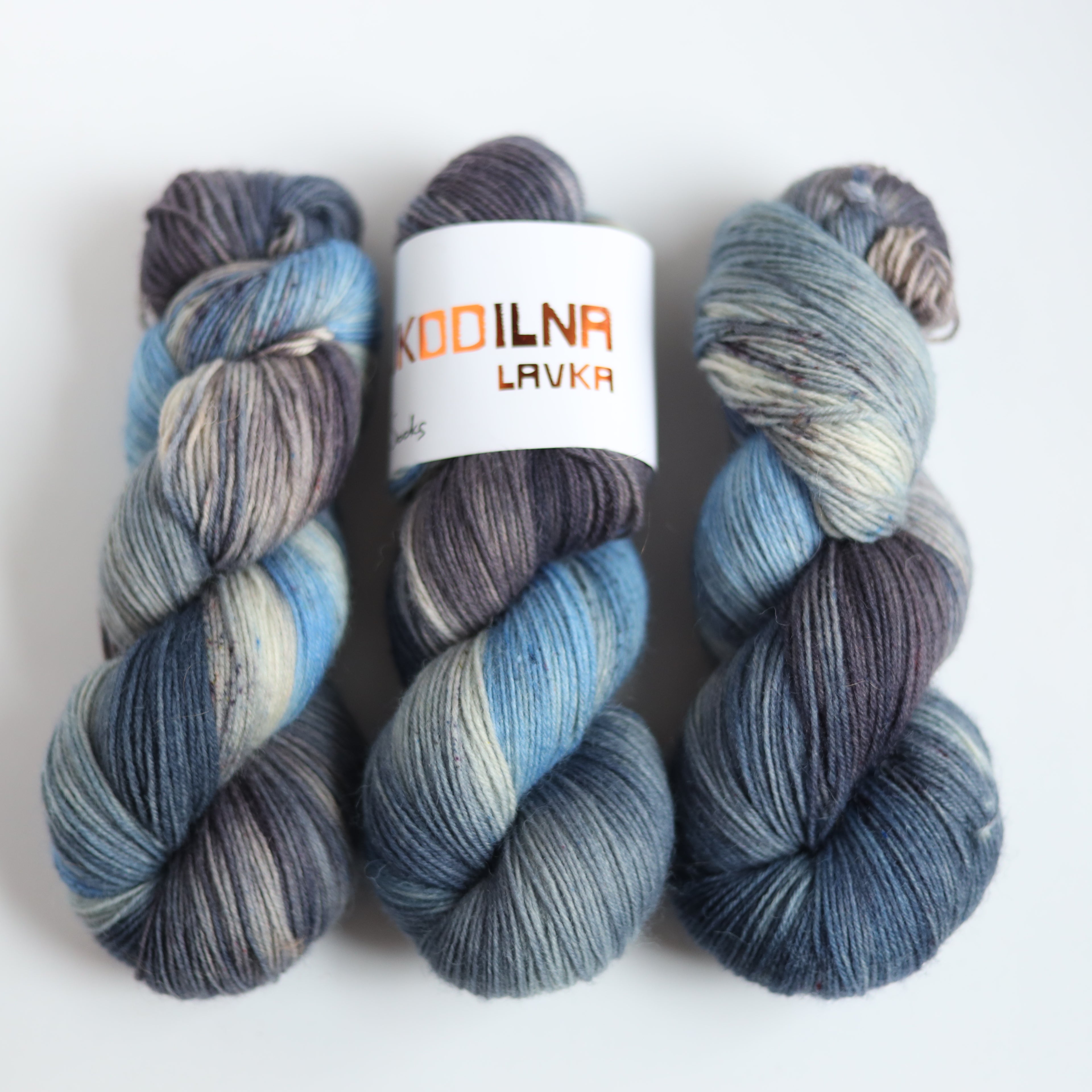 Hand dyed sock yarn in blue and grey tones made from Italian superwash wool, fingering weight 4-ply yarn on white background
