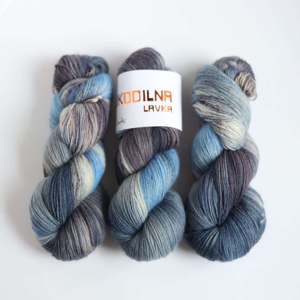 Hand dyed sock yarn in blue and grey tones made from Italian superwash wool, fingering weight 4-ply yarn on white background