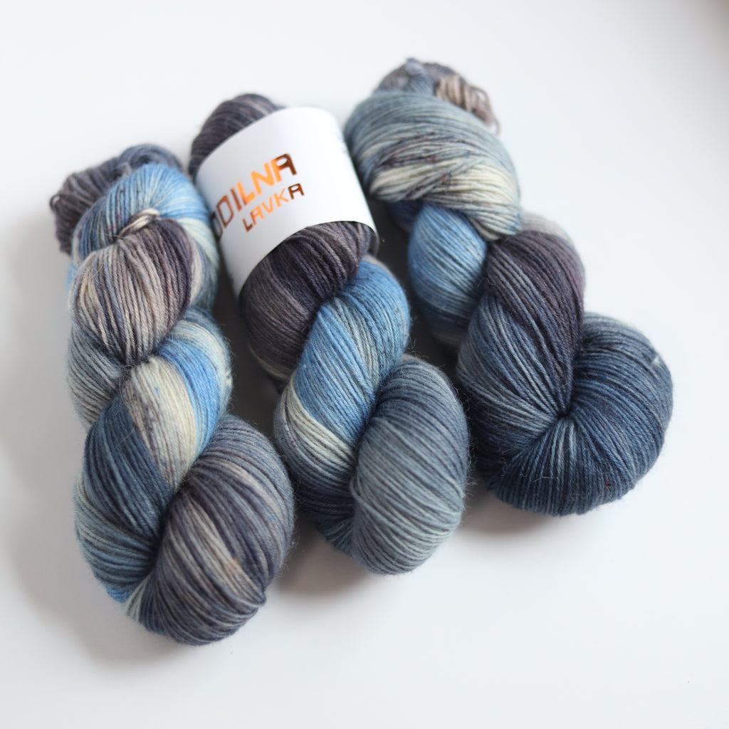 Hand dyed sock yarn in blue and grey tones made from Italian superwash wool, fingering weight 4-ply yarn on white background