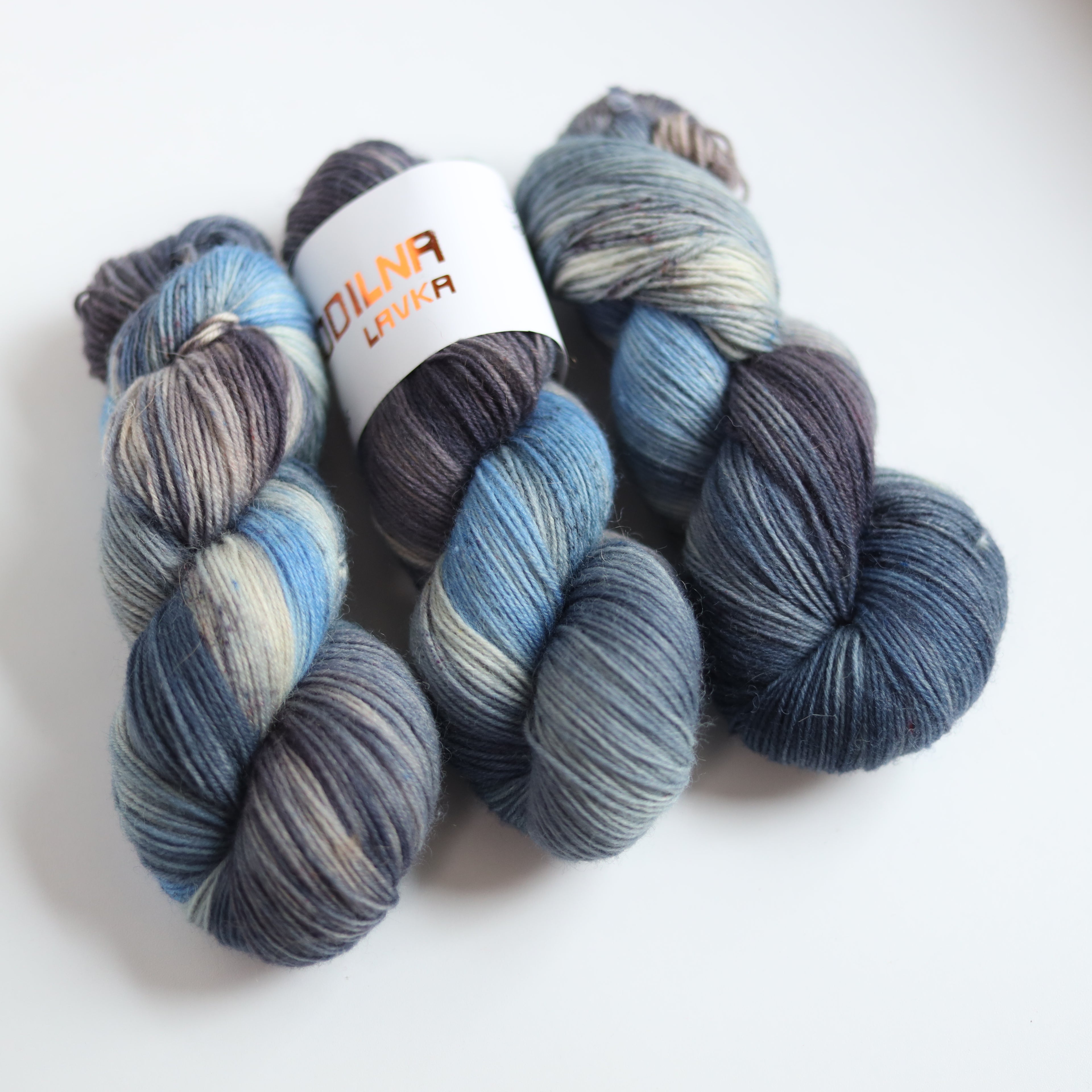 Hand dyed sock yarn in blue and grey tones made from Italian superwash wool, fingering weight 4-ply yarn on white background