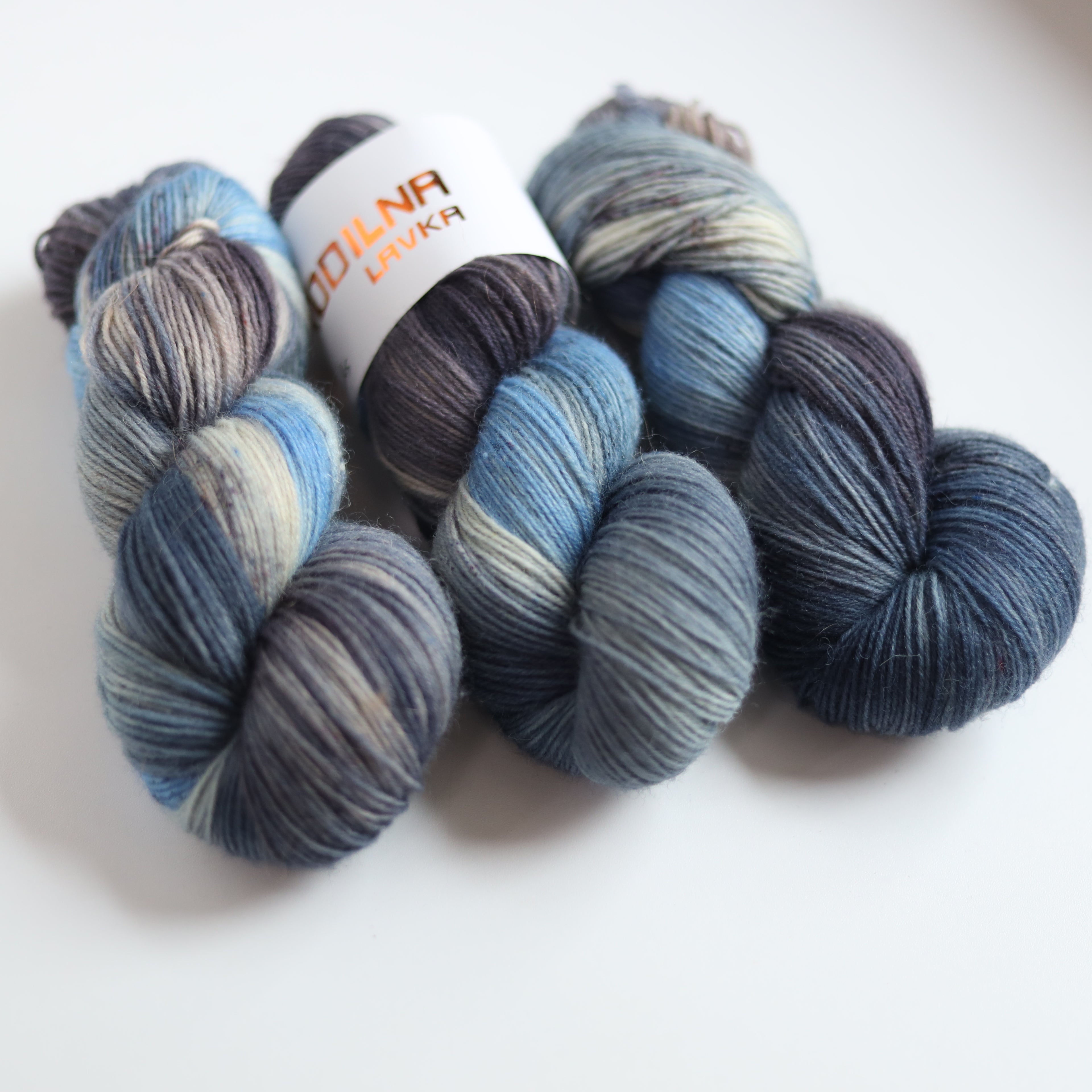 Hand dyed sock yarn in blue and grey tones made from Italian superwash wool, fingering weight 4-ply yarn on white background