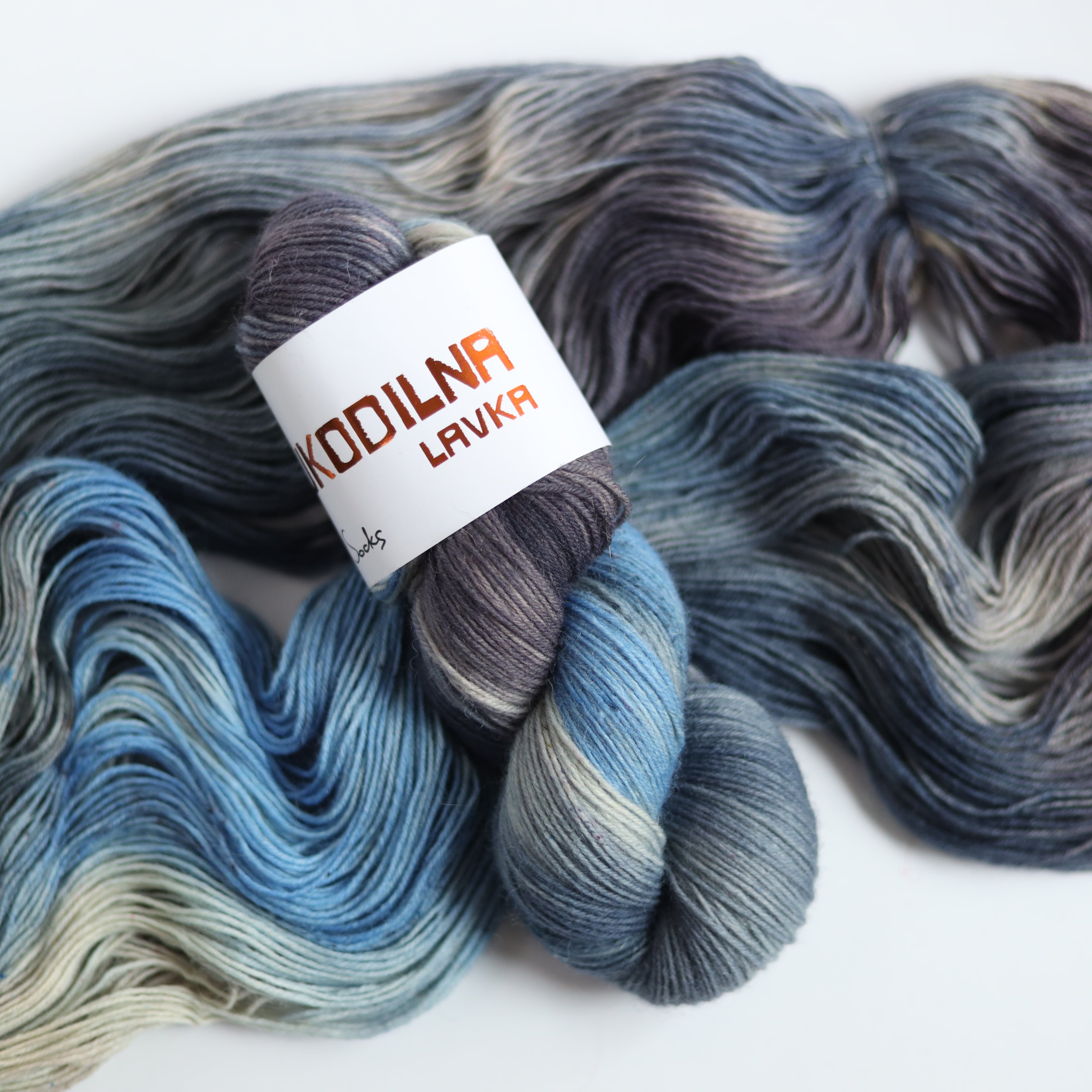 Hand dyed sock yarn in blue and grey tones made from Italian superwash wool, fingering weight 4-ply yarn on white background