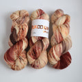 Hand dyed sock yarn skeins in warm brown and beige variegated tones on a white background