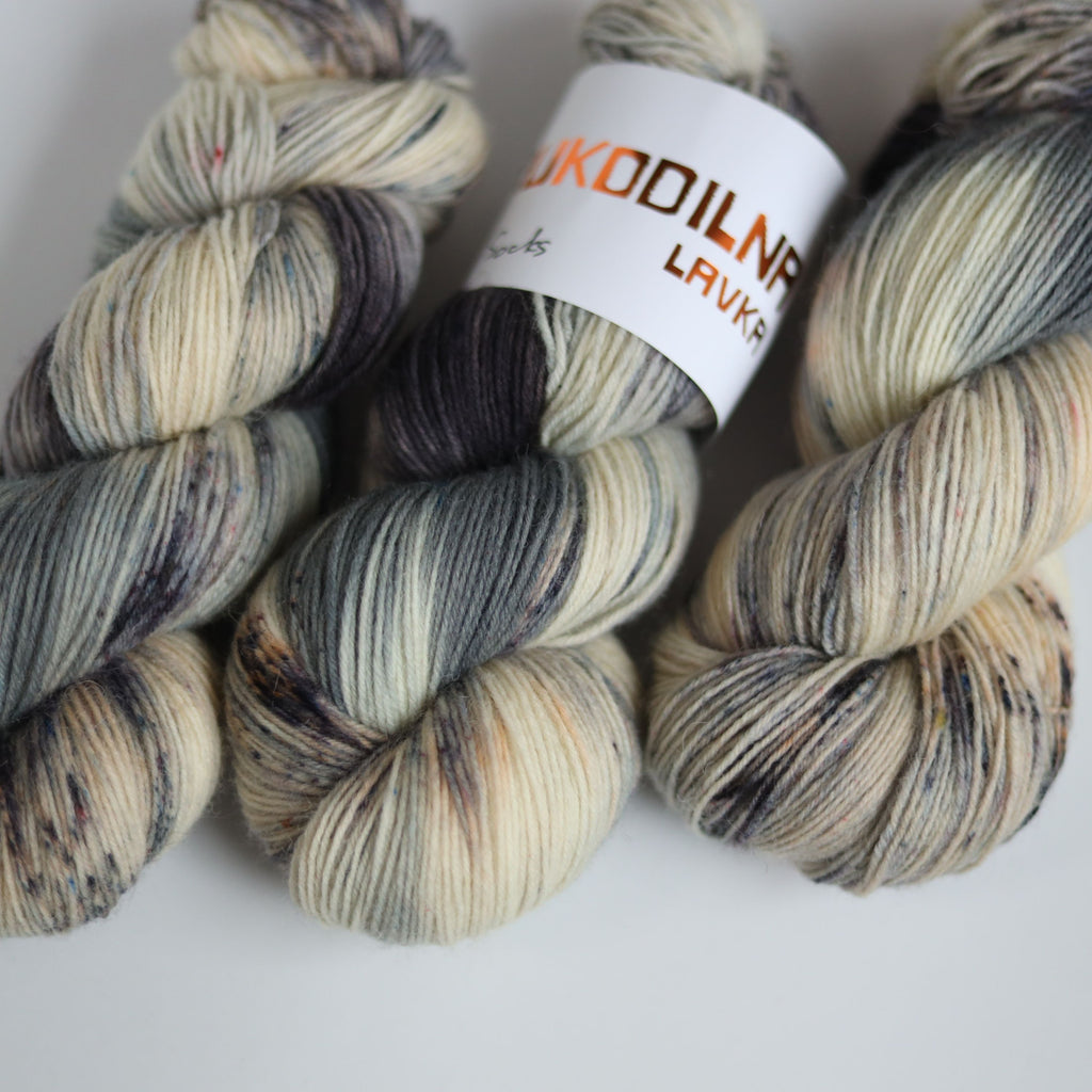Hand dyed fingering weight sock yarn skein on knitted fabric, variegated wool yarn for socks