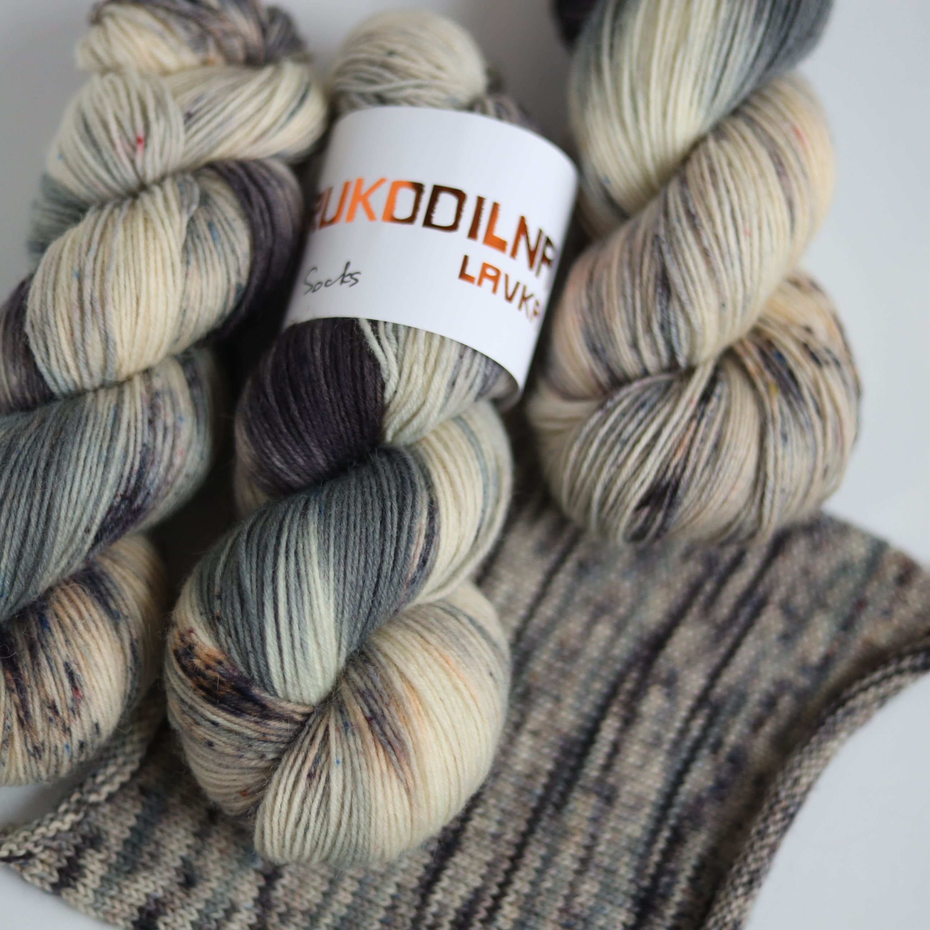 Hand dyed fingering weight sock yarn skein on knitted fabric, variegated wool yarn for socks