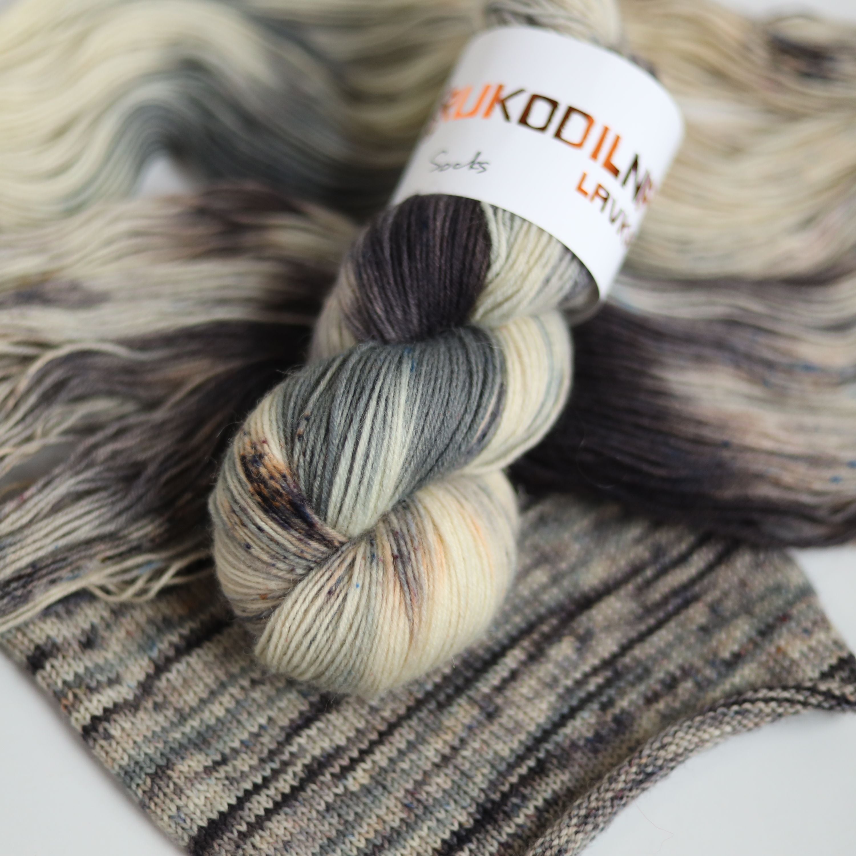Hand dyed fingering weight sock yarn skein on knitted fabric, variegated wool yarn for socks