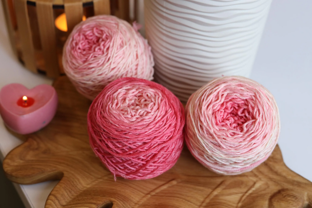 Hand dyed pink gradient merino wool yarn cakes in blush, rose, and soft pink shades, 100% merino wool DK weight yarn for knitting and crochet.