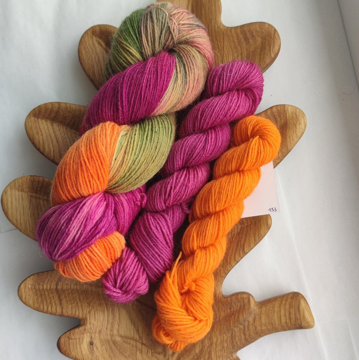 Hand dyed sock yarn gift set featuring a variegated skein in berry pink, orange and olive green shades paired with matching mini skeins. Fingering weight yarn bundle for knitters.