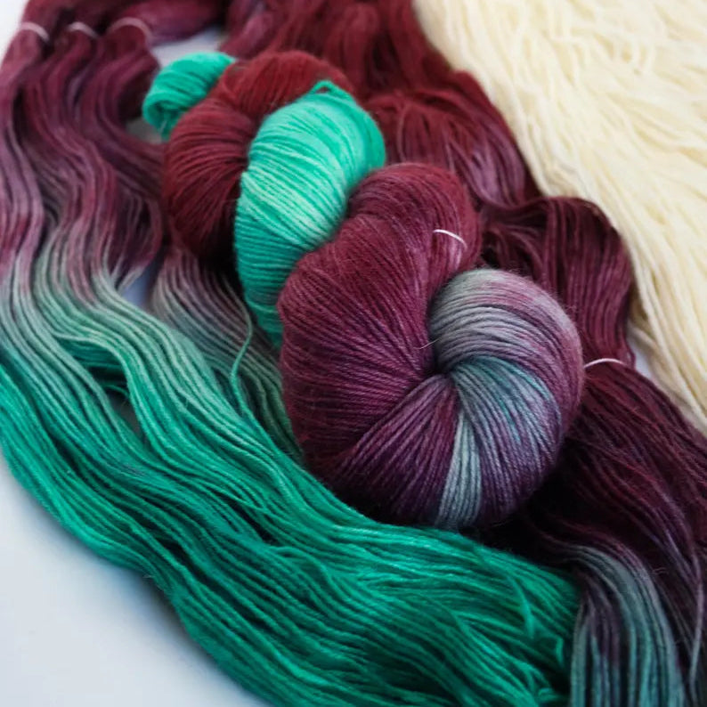 Hand dyed sock yarn set with a dark purple variegated skein and emerald green mini skein for contrast heels, toes and colorful sock knitting projects.