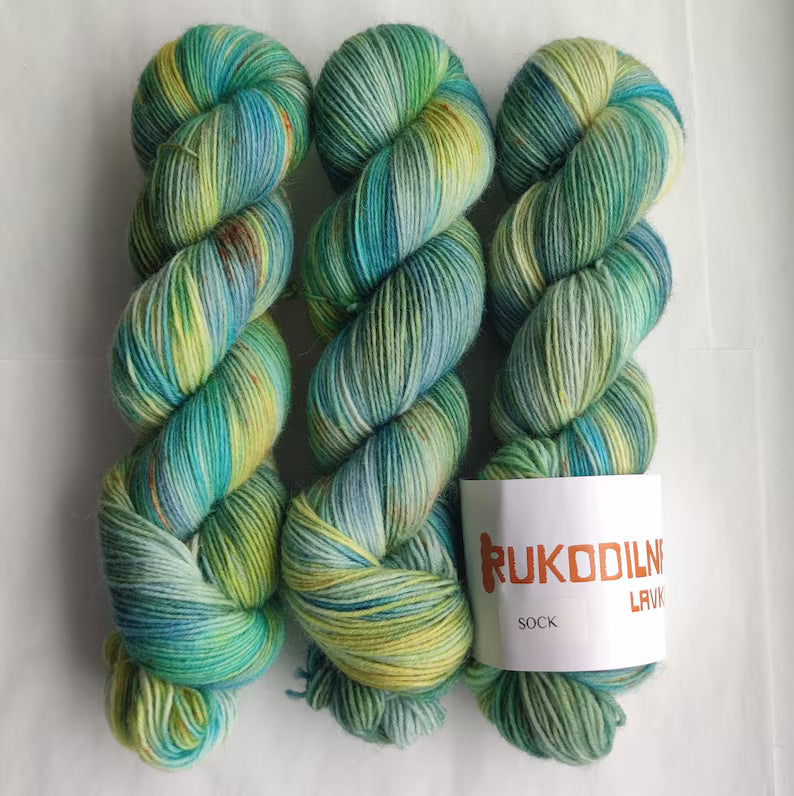 Hand dyed variegated wool nylon sock yarn in green, aqua blue and pale yellow shades, fingering weight knitting yarn for socks and shawls.