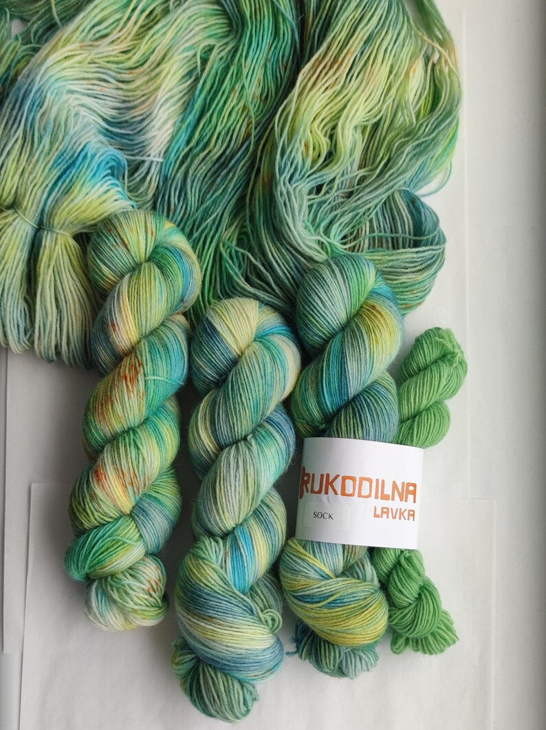 Hand dyed variegated wool nylon sock yarn in green, aqua blue and pale yellow shades, fingering weight knitting yarn for socks and shawls.