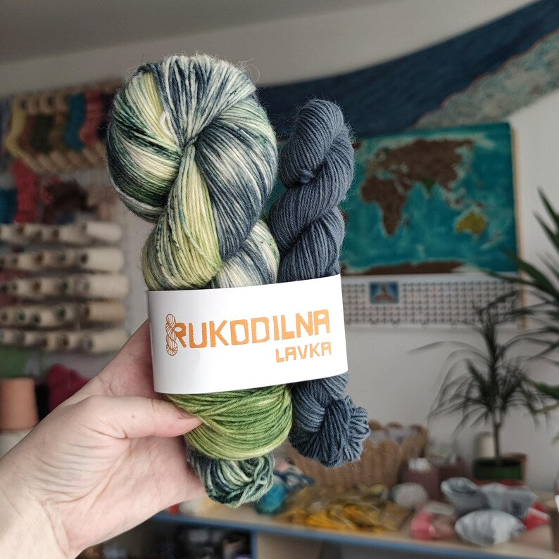 Full skein and mini skein sock yarn set with hand dyed variegated yarn in sage green, cream and blue-grey shades paired with a smoky blue mini skein.